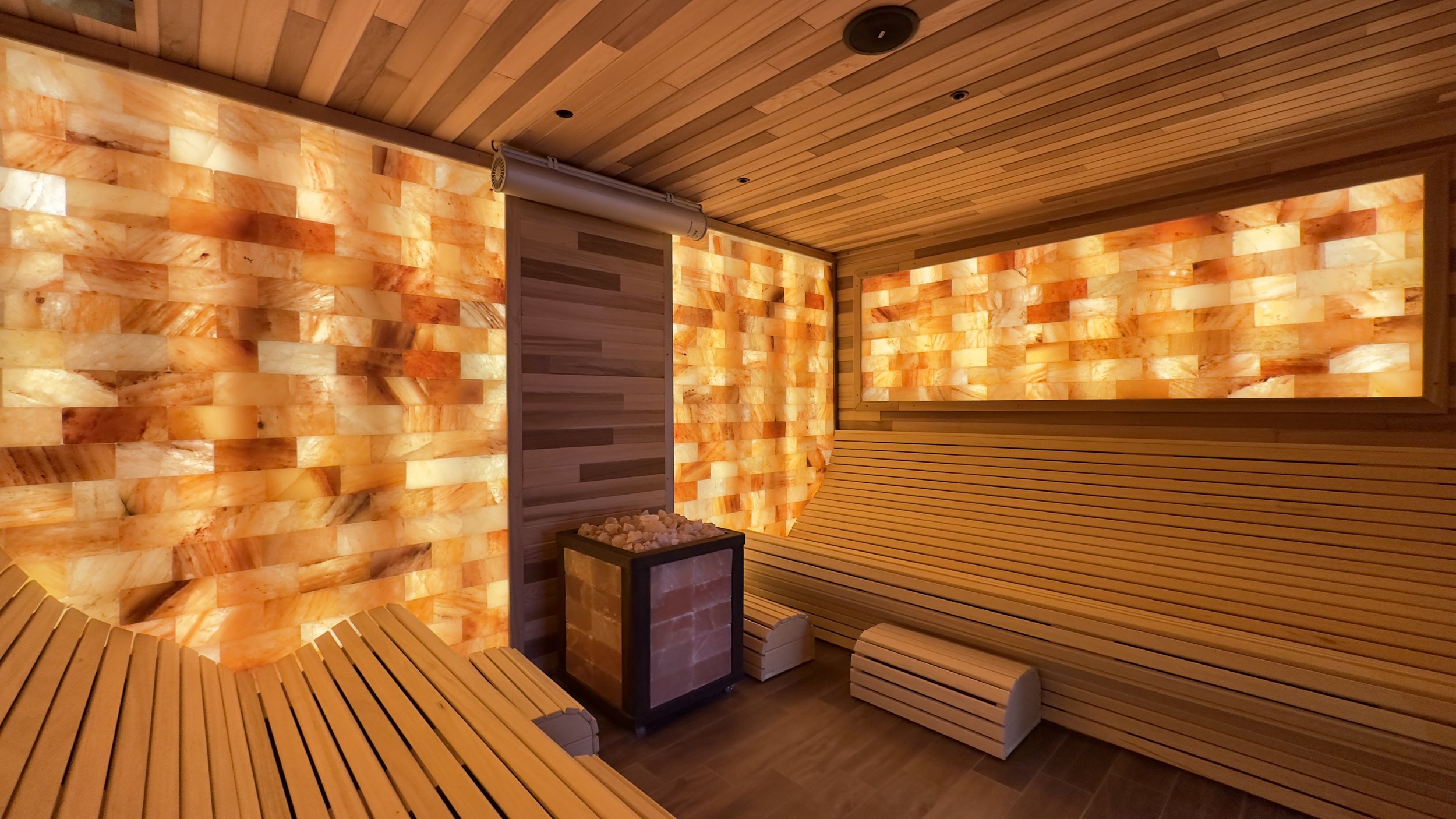 Salt room with Himalayan salt wall panels, wood benches, and a salt-brick heater.