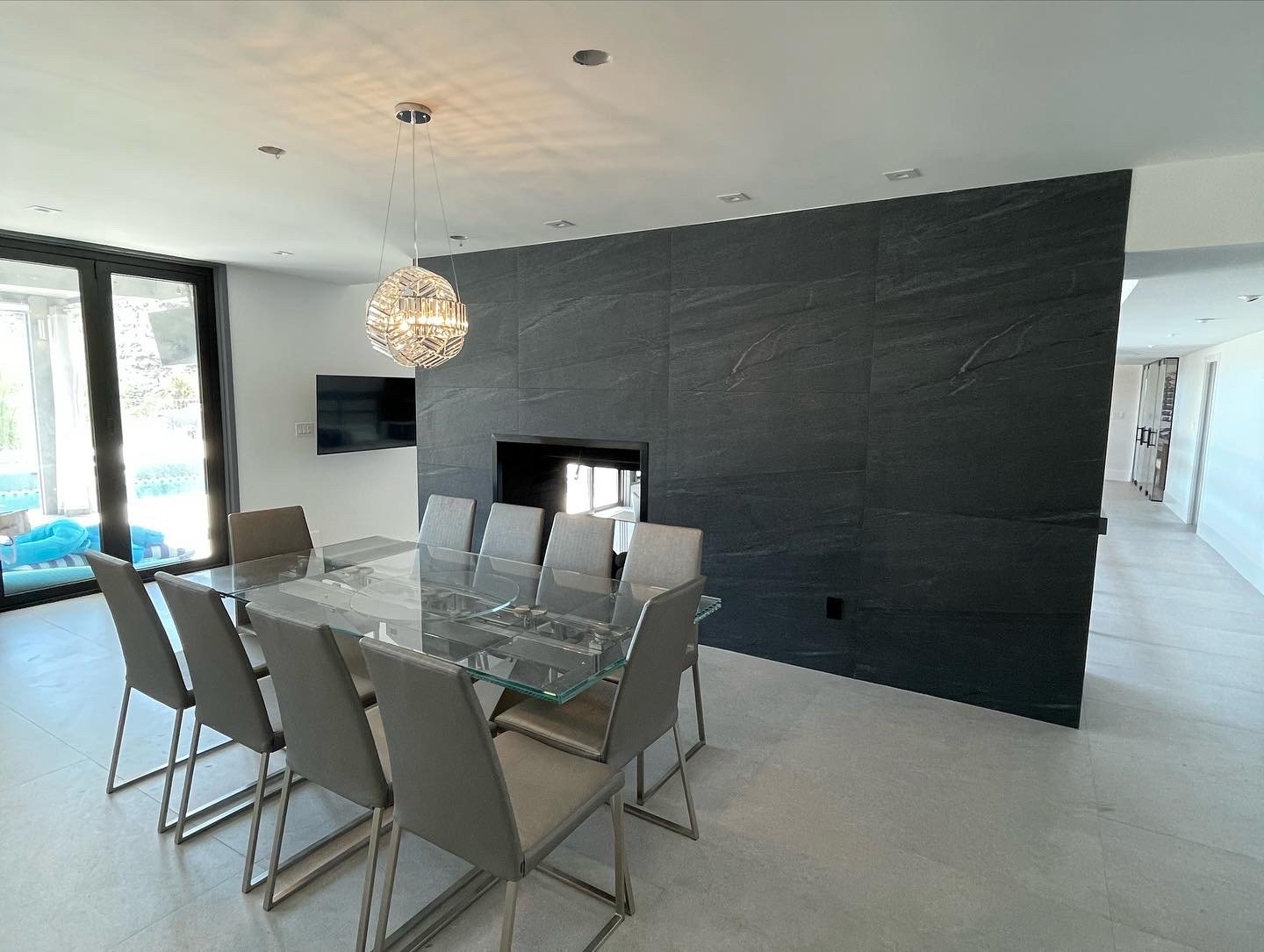 Renovated dining room with a glass table, a black fireplace, and sliding doors to a patio.