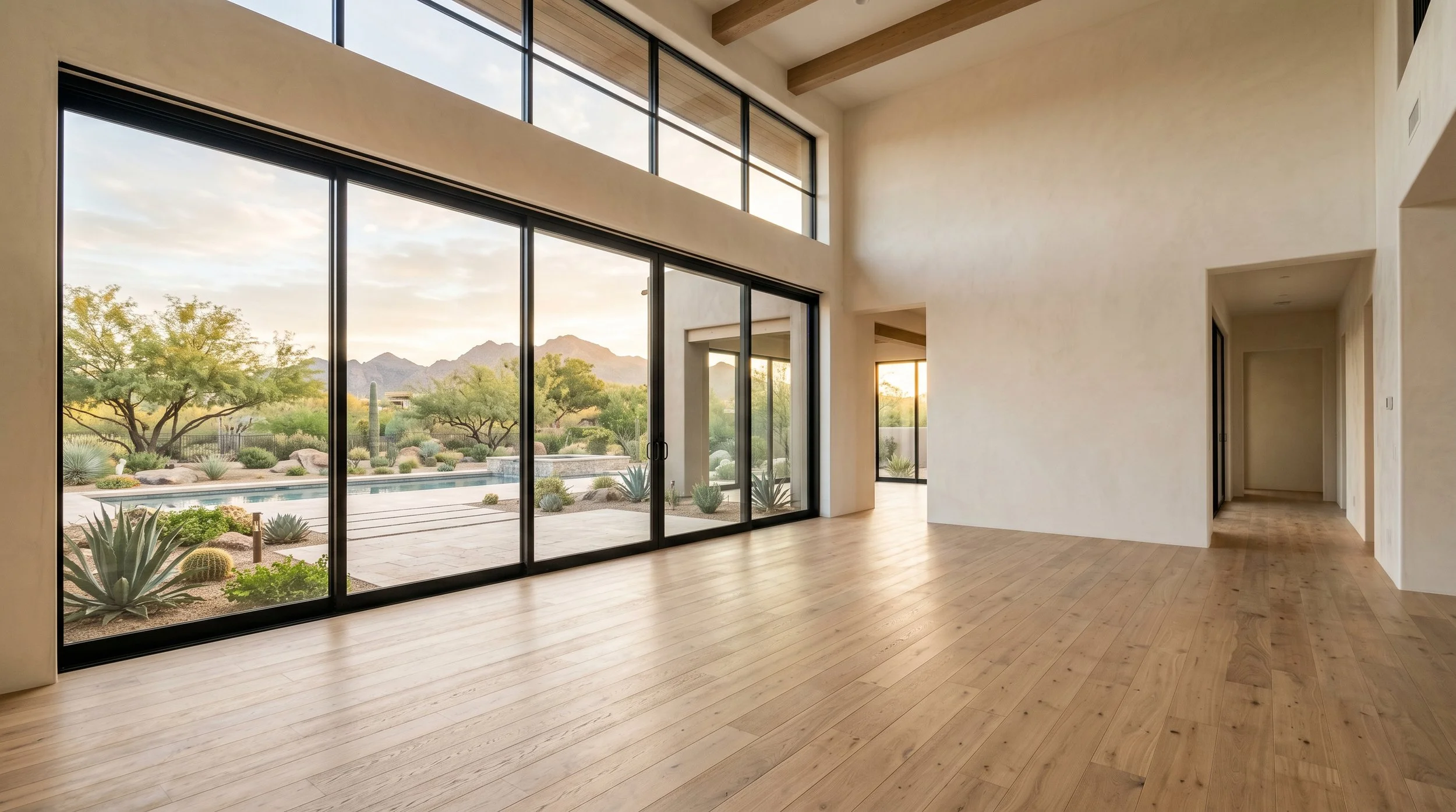Open living space wrapped in floor-to-ceiling glass, framing the desert and pool beyond.