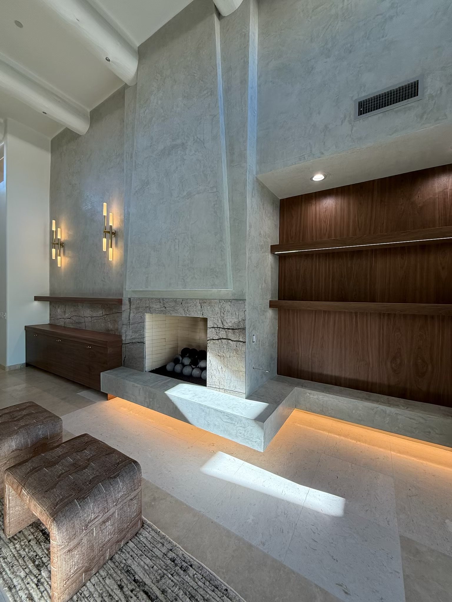 Renovated living room with a gray stone fireplace, wood wall paneling, and a striped sofa.