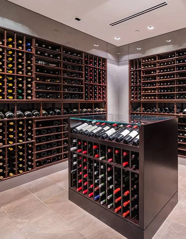 Walk-in wine cellar with dark wood racking on all sides and a central display island.