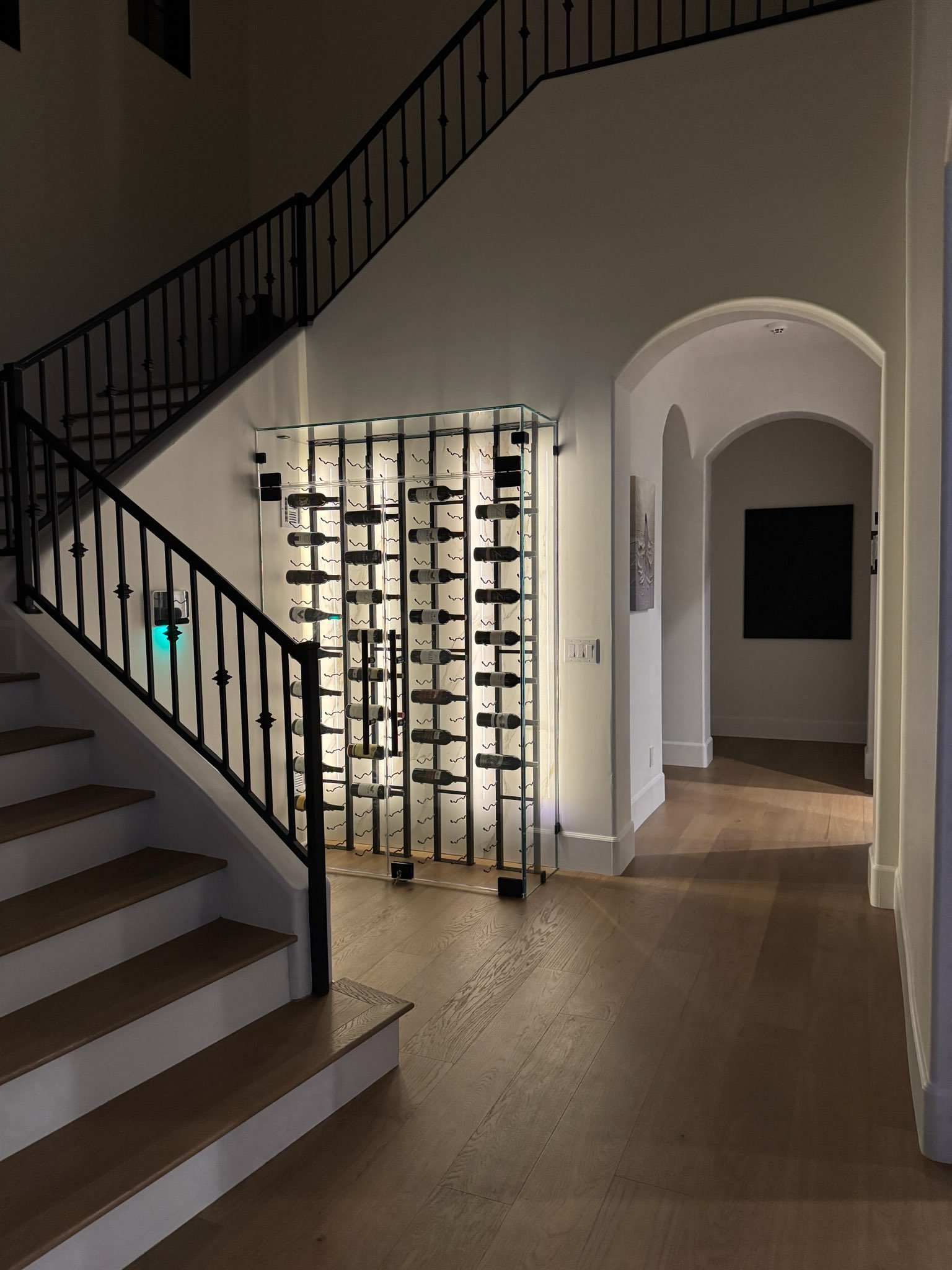 Home entry with a wood staircase and a built-in wine display beneath arched openings.