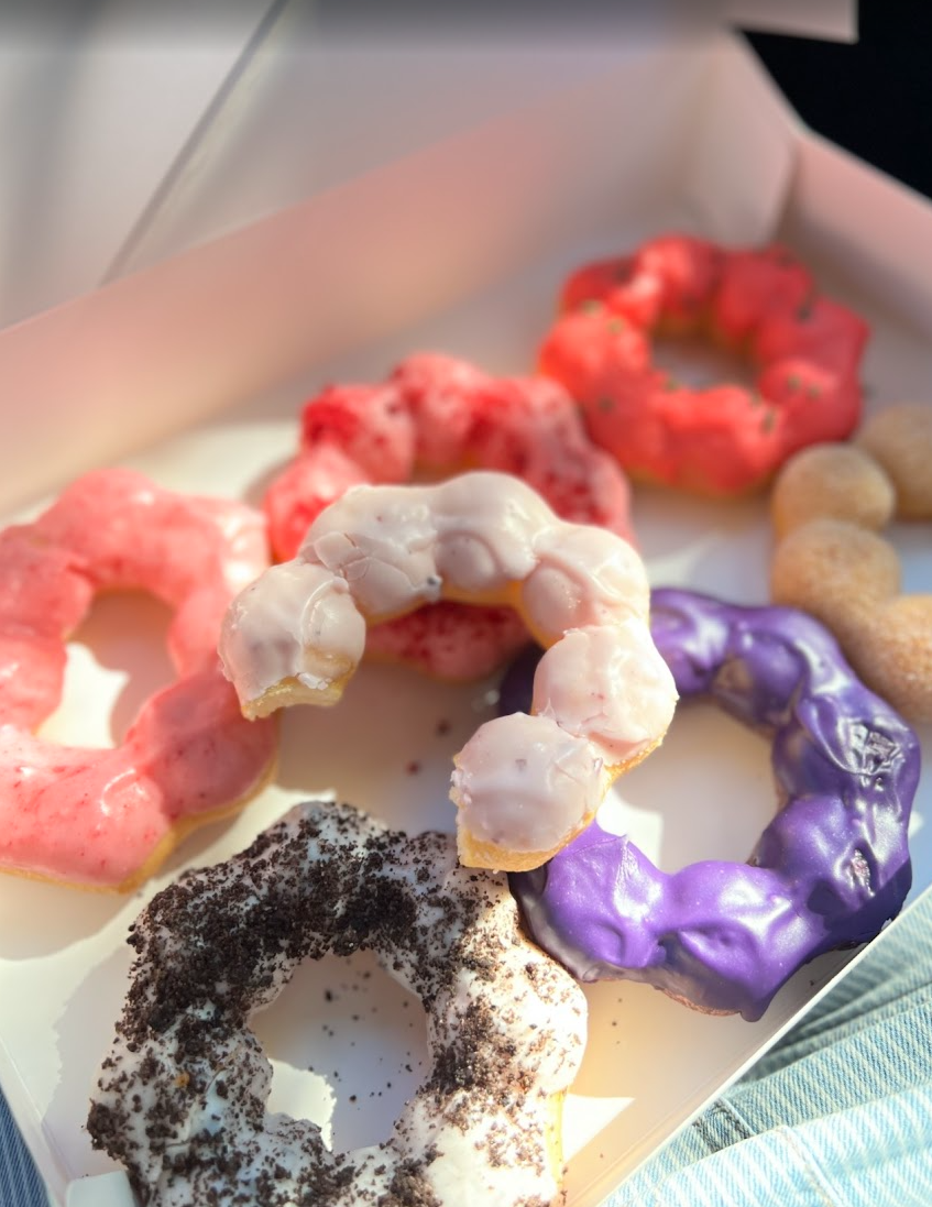 An assortment of colorful donuts with various frostings and toppings in a box.