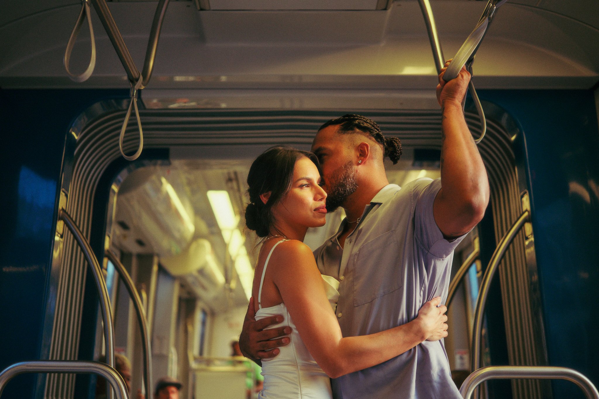 A couple kissing inside a bus, with the man holding onto a handrail.