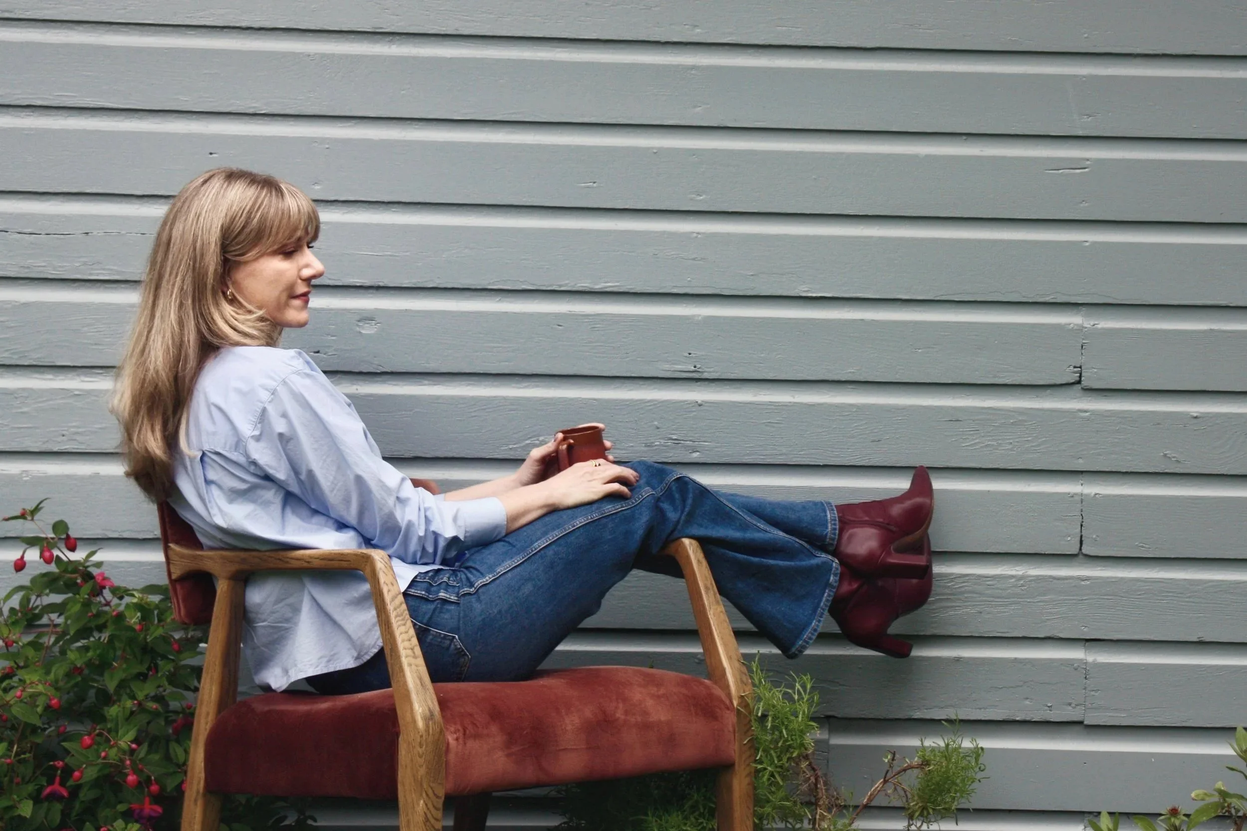 Alyssia Haymond, licensed therapist, sitting in chair and holding a coffee mug.