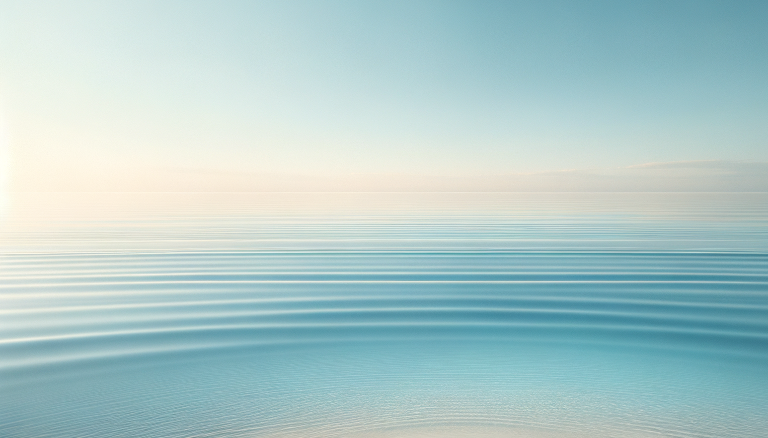 Calm ocean water with ripples under a clear sky, horizon in the distance.