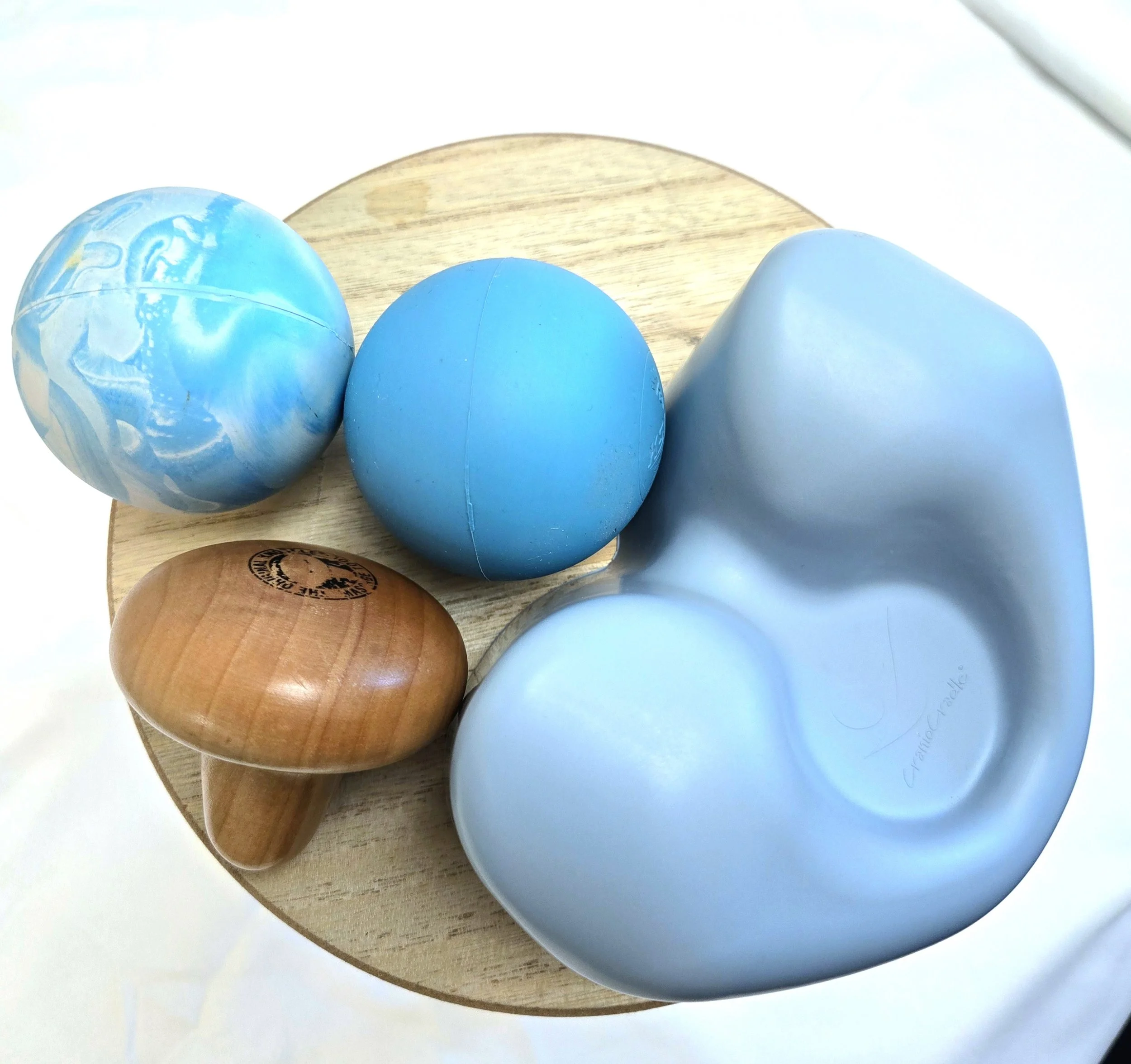 Close-up image of light blue and natural wood-colored eggs on a round wooden tray.