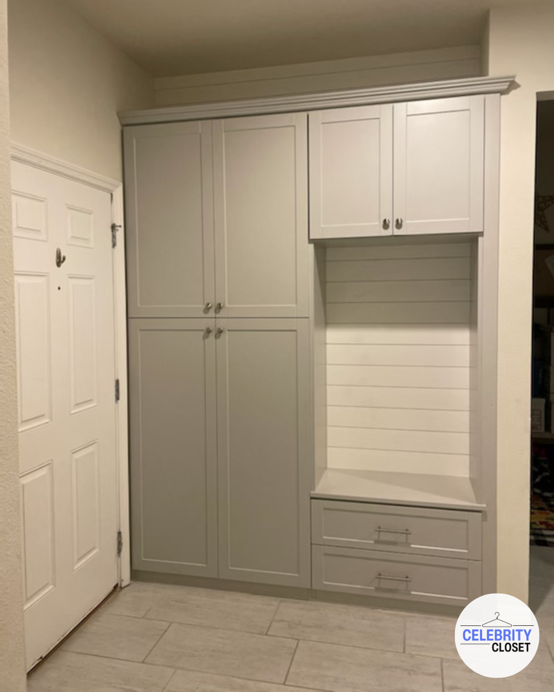 White closet unit next to a door with a white wooden door and silver handle, featuring cabinet doors, drawers, and open shelving.