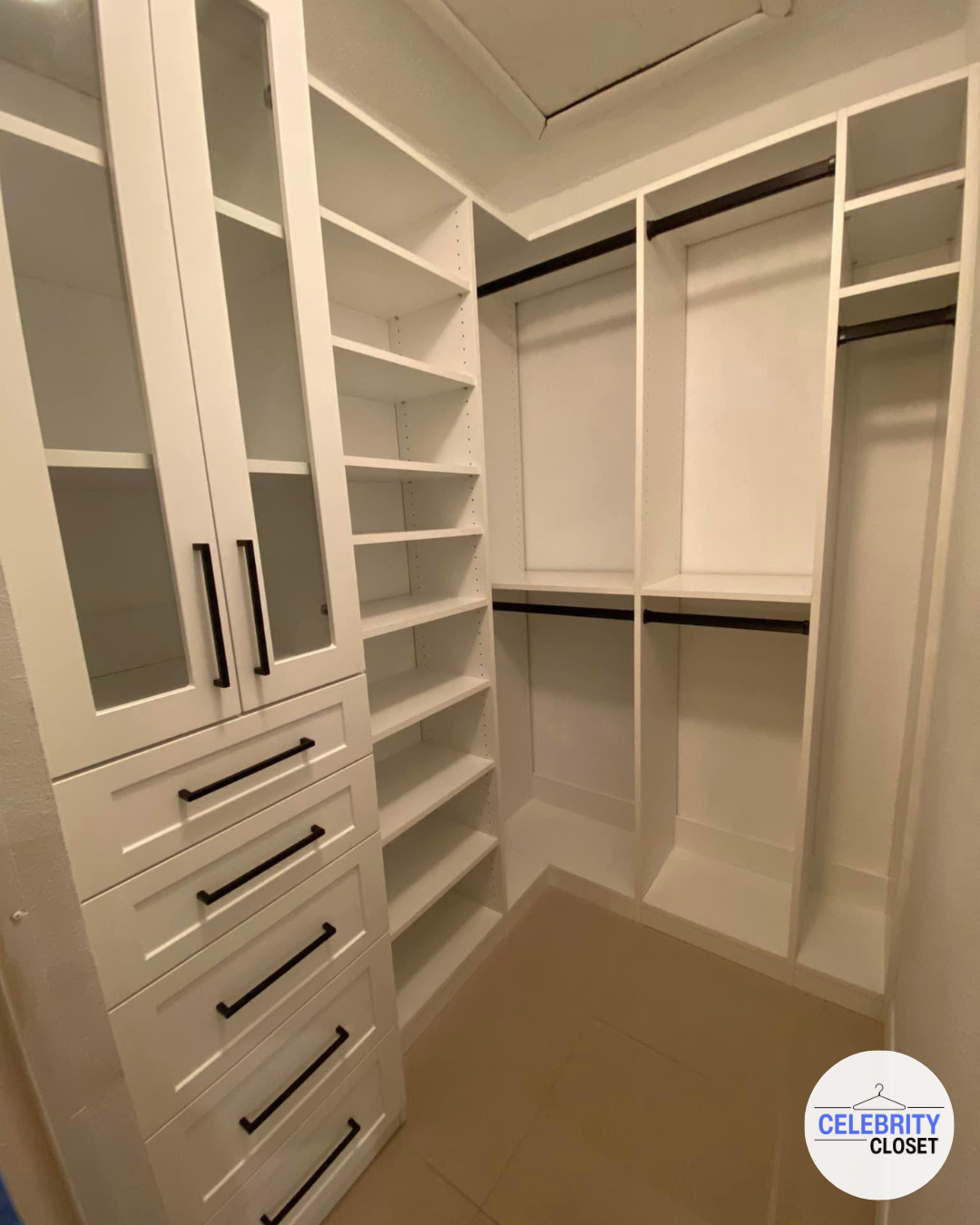Empty white walk-in closet with shelves, drawers, and hanging rods.