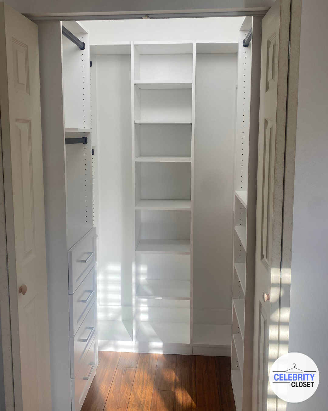 Empty white closet with shelves and drawers, open sliding doors, and hardwood flooring.