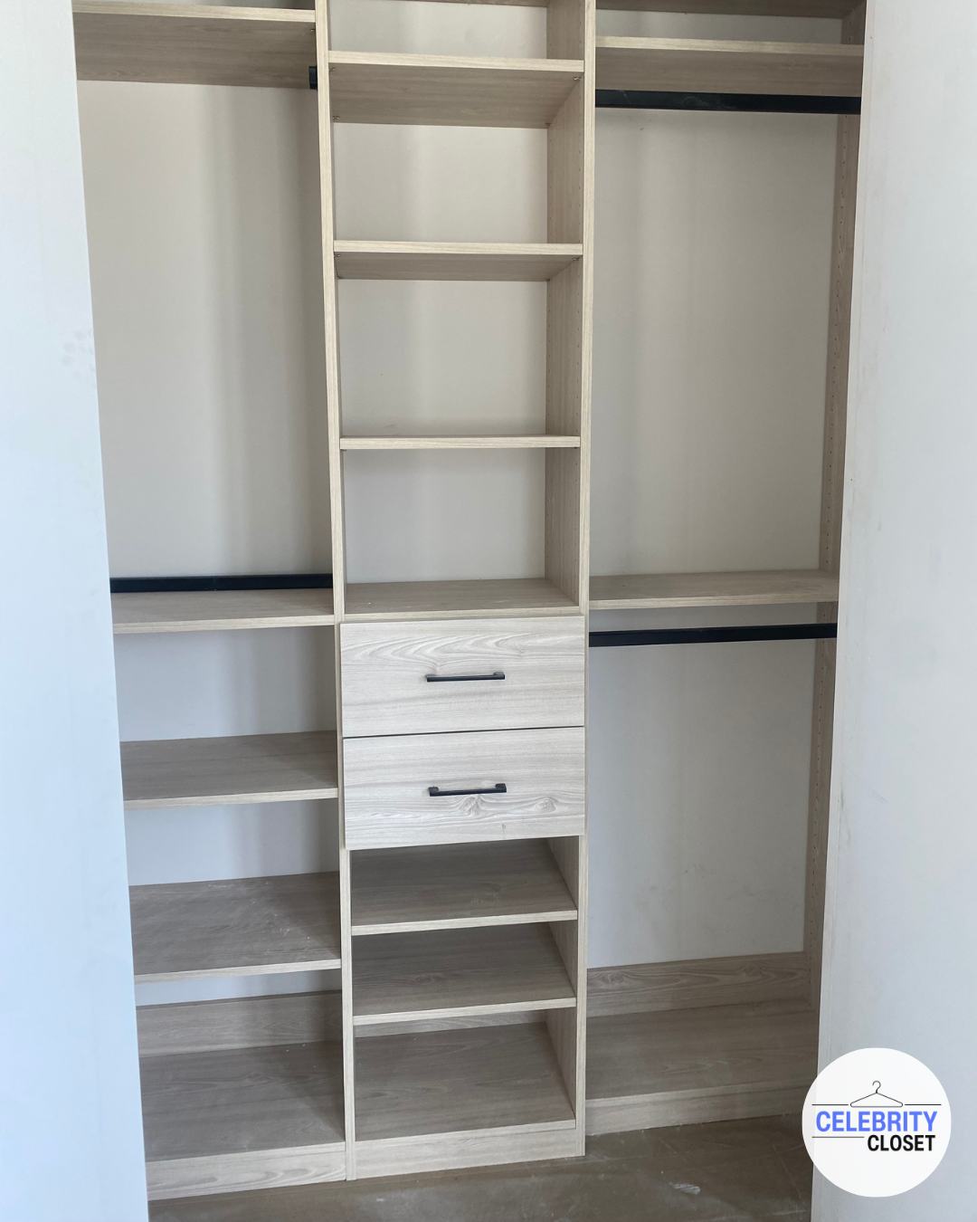 Light wood empty closet with multiple shelves, two drawers, and hanging rods.