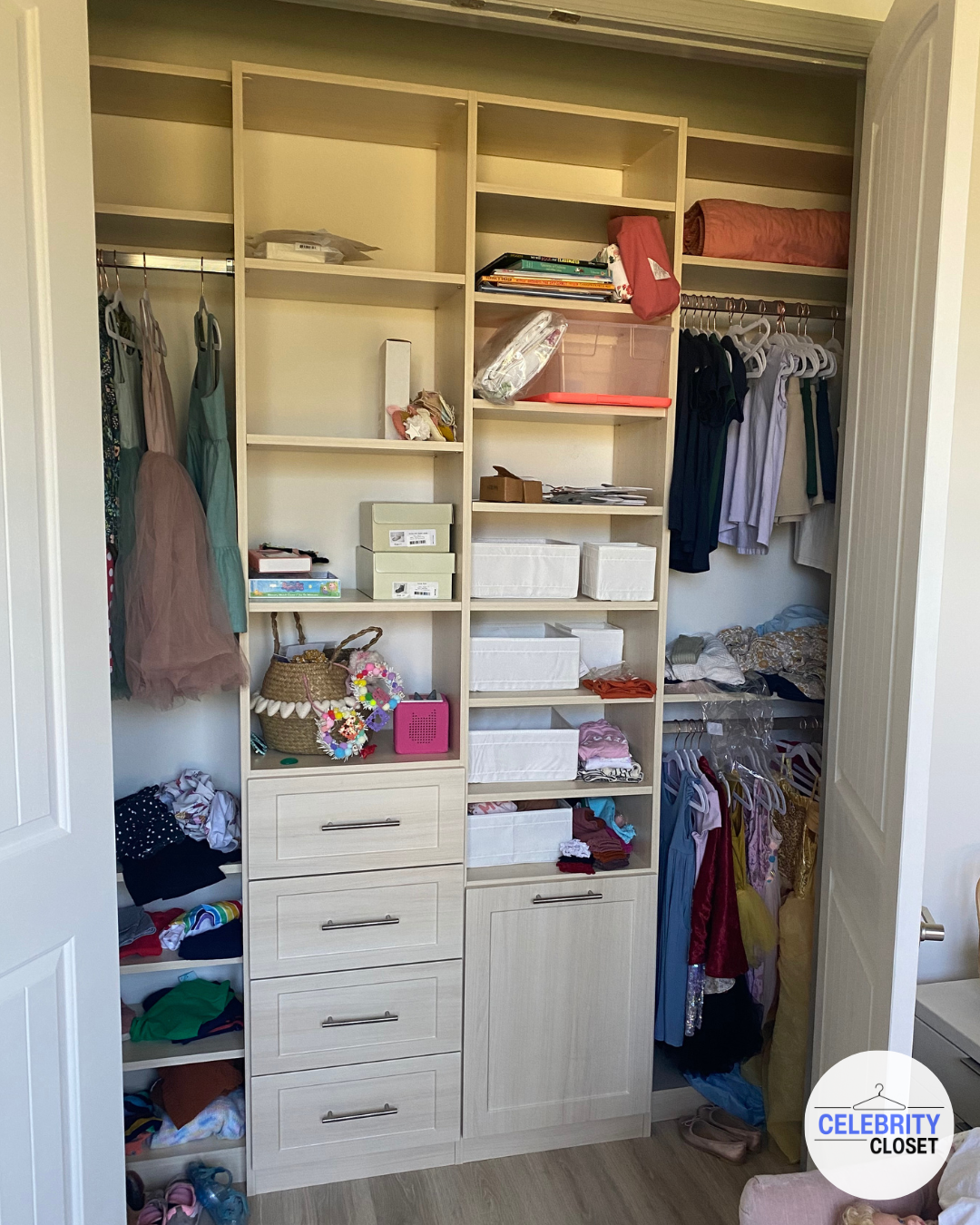 Open closet with various shelves, drawers, and hanging space for clothes, shoes, and accessories, some clothes are hanging and some are folded or stored in boxes.