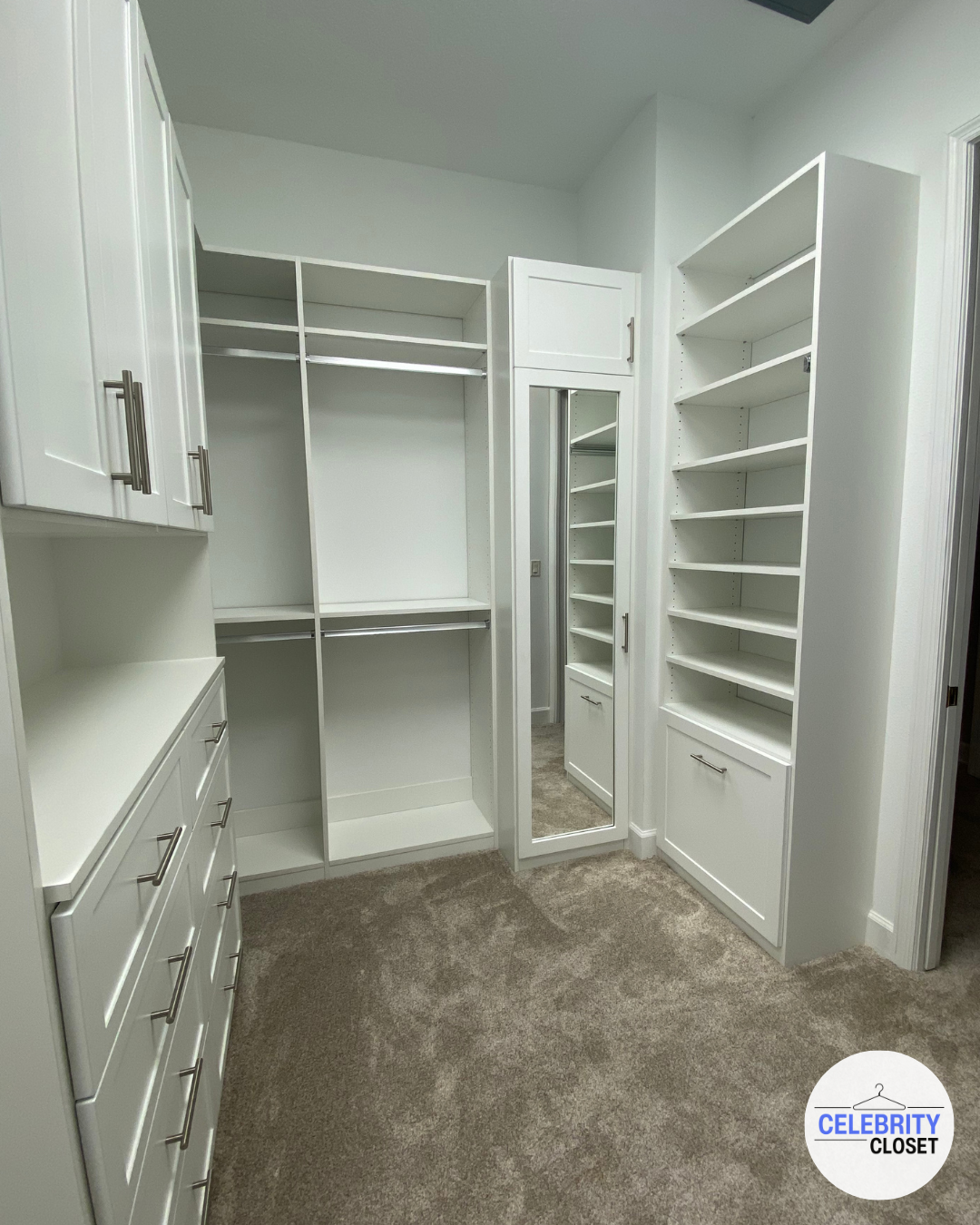 Empty white walk-in closet with shelves, drawers, and a full-length mirror.