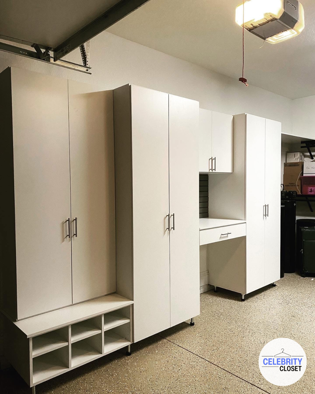 White storage cabinets with handles and open shelves in a garage space.