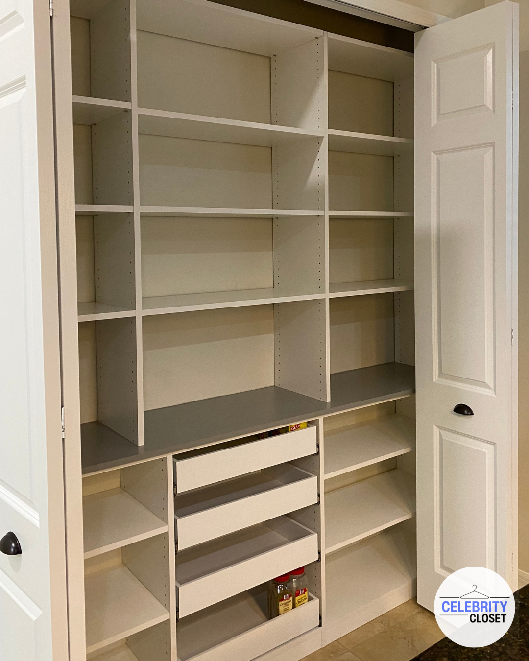 Empty white closet with multiple shelves, drawers, and food spice jars at bottom right.