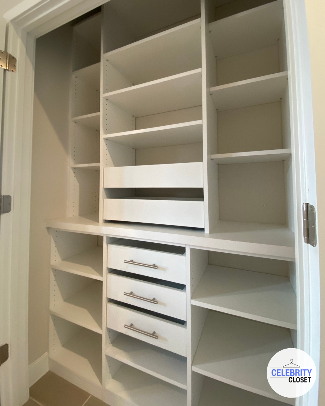 Empty white custom closet organizer with multiple shelves, drawers, and compartments.