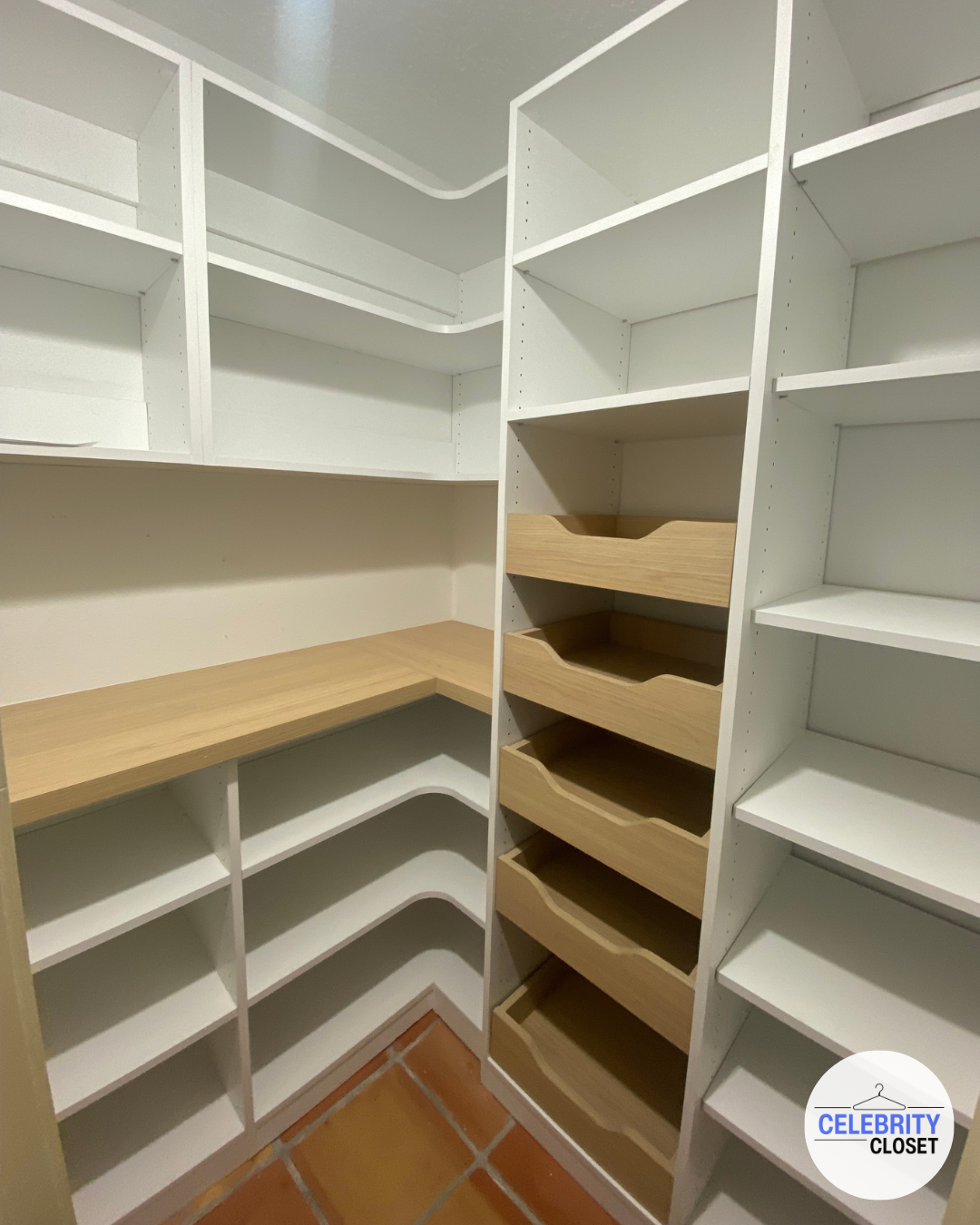 Empty white and tan built-in closet with shelves and drawers.