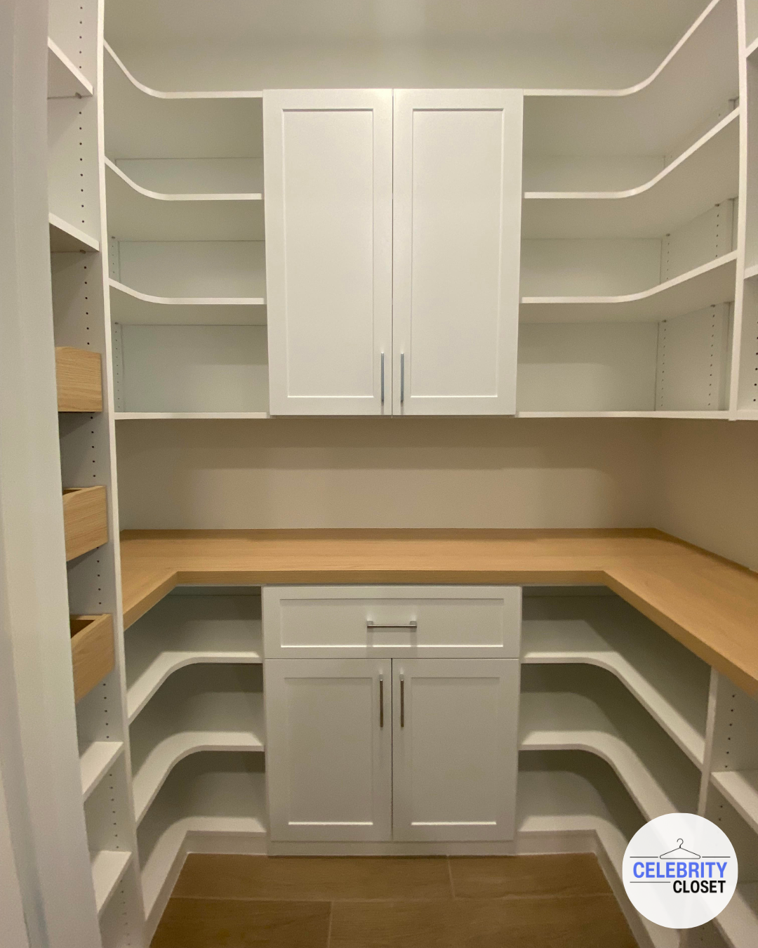 Empty white and wood corner closet with shelves, cabinets, and drawers.