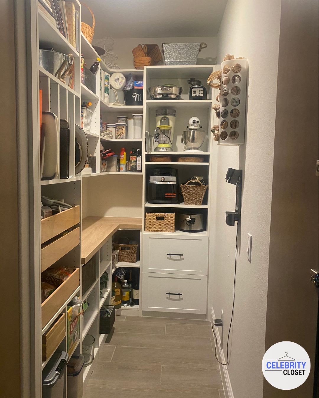 Organized pantry with shelves holding kitchen appliances, jars, baskets, spices, and cooking supplies.