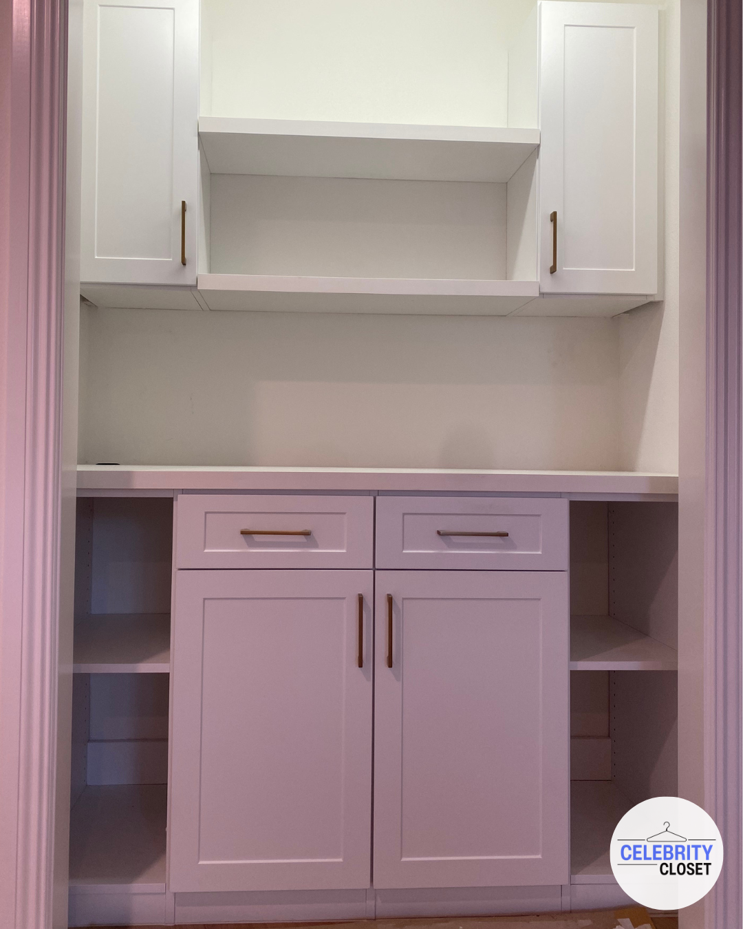 Empty white built-in kitchen or closet cabinets with gold handles and open shelves.