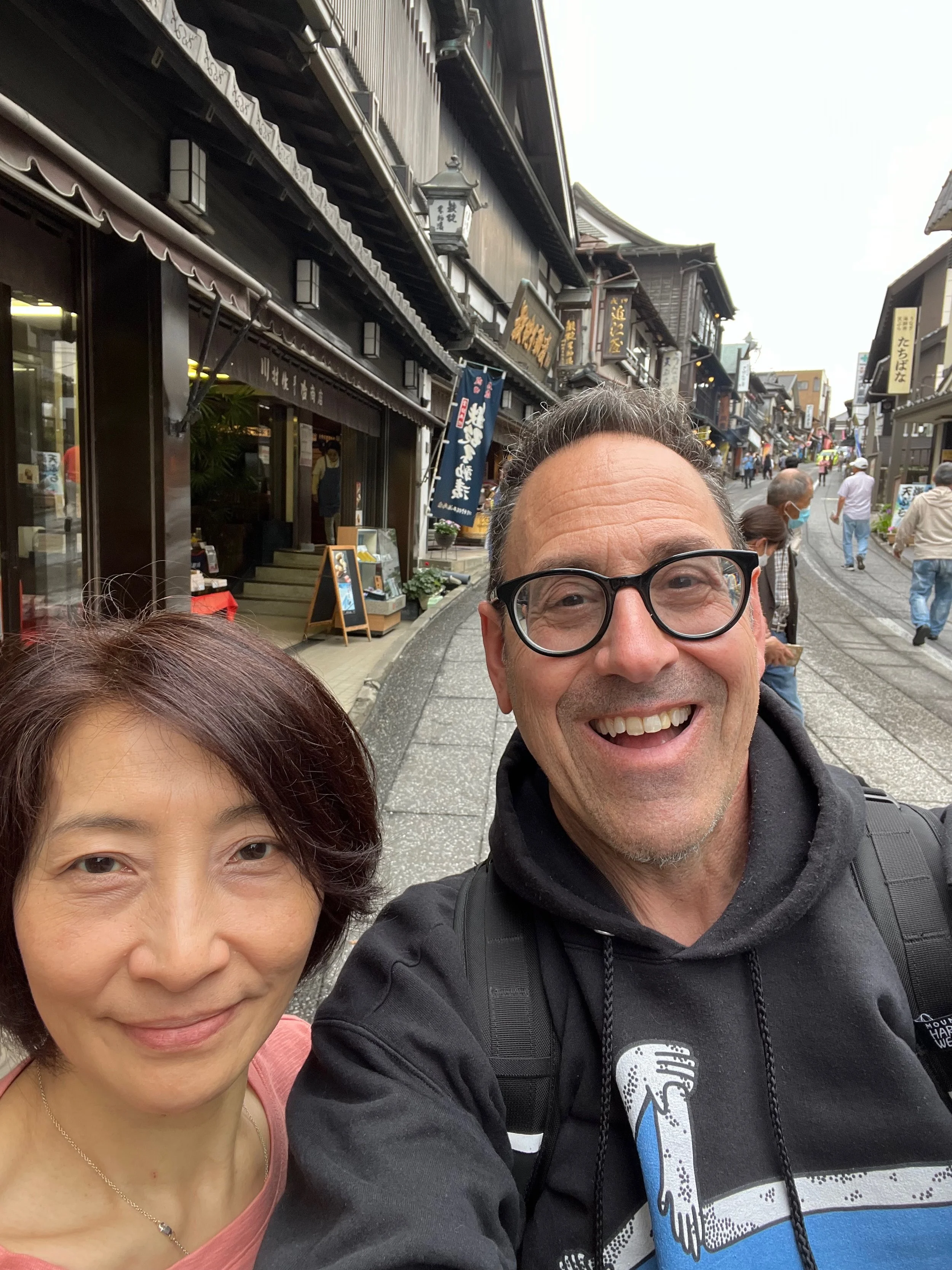Gil Aranowitz and his wife Shizue smiling on a historic shopping street in Narita, Japan.