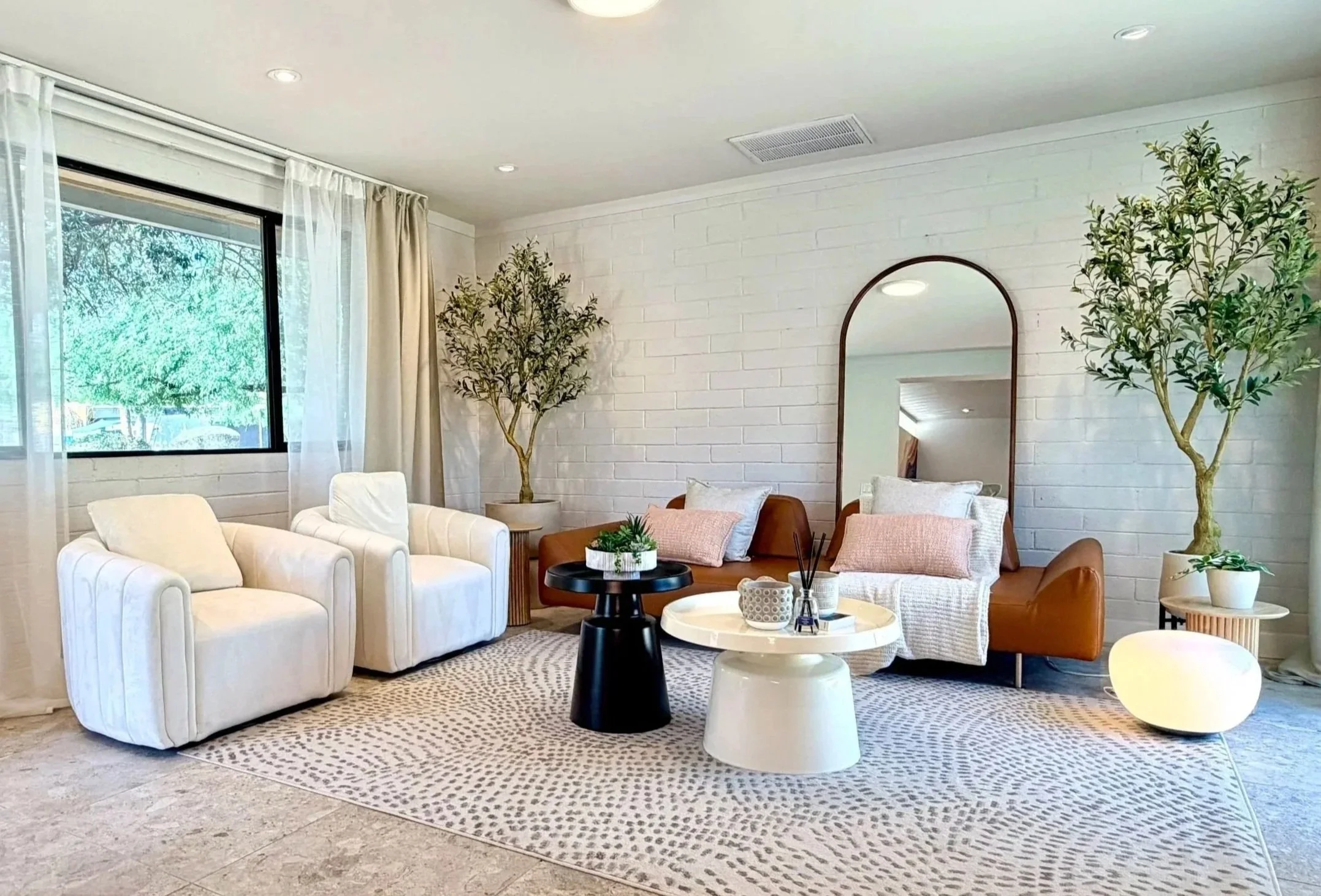 Bright modern creative studio rental in North Phoenix with natural light, white brick walls, plants, soft seating, and styled photo areas.