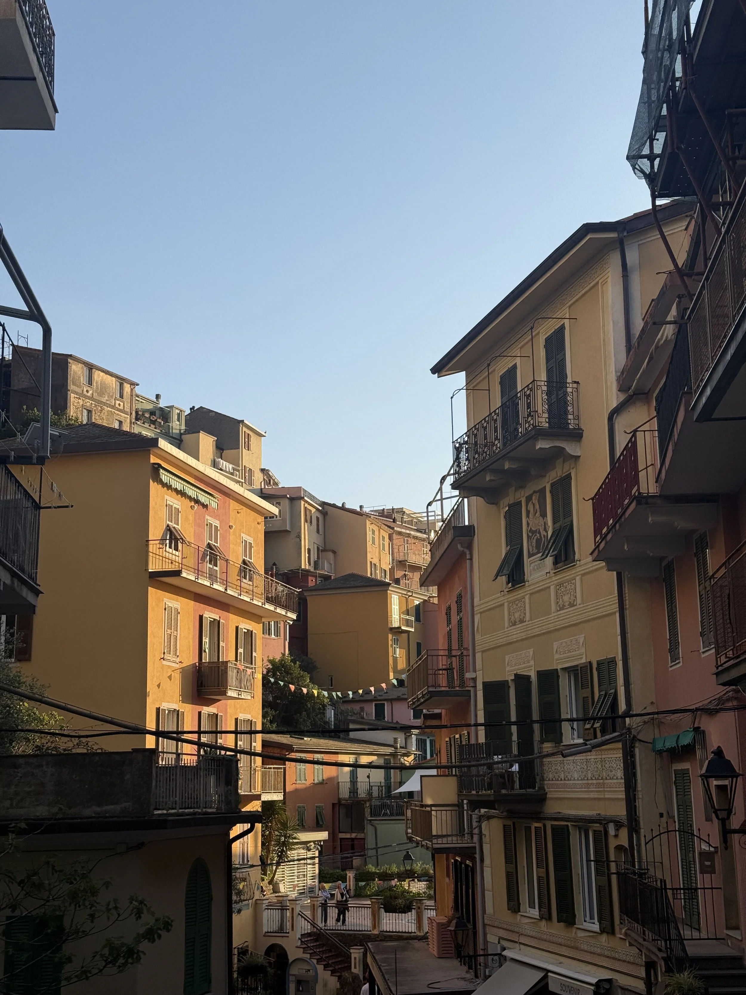 View of colorful European-style apartment buildings with balconies, windows, and laundry hanging outside, under a clear blue sky.