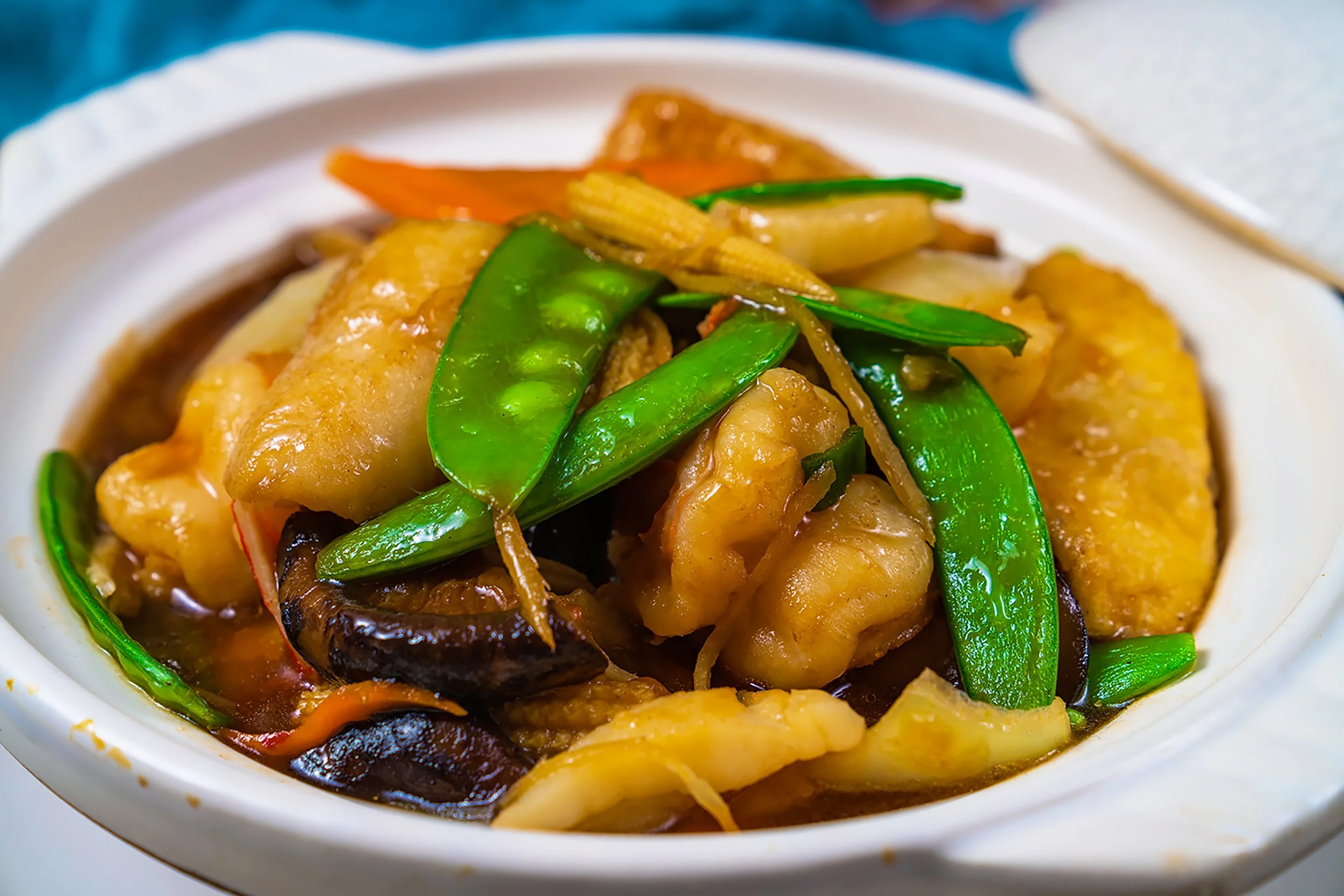 Close-up of a dish with vegetables and possibly chicken in a sauce, served in a white bowl.