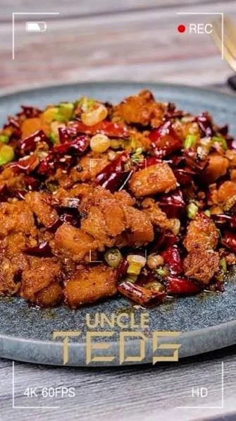 A plate of spicy fried chicken stir-fried with dried red chili peppers and chopped green onions.