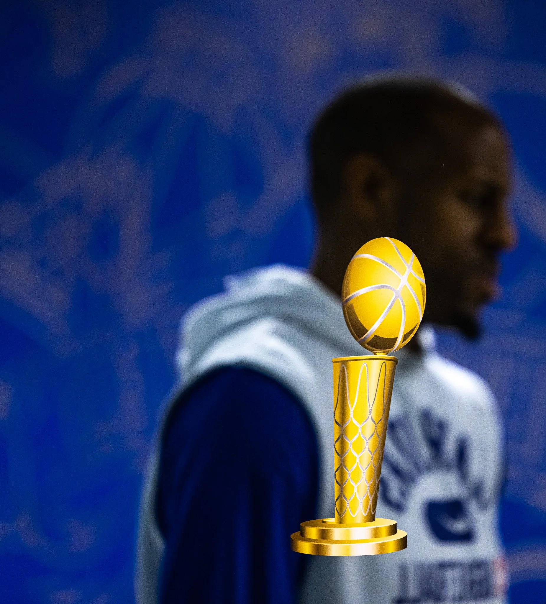 Close-up of a golden trophy with a basketball design on top, set against a dark blue background with blurred text.
