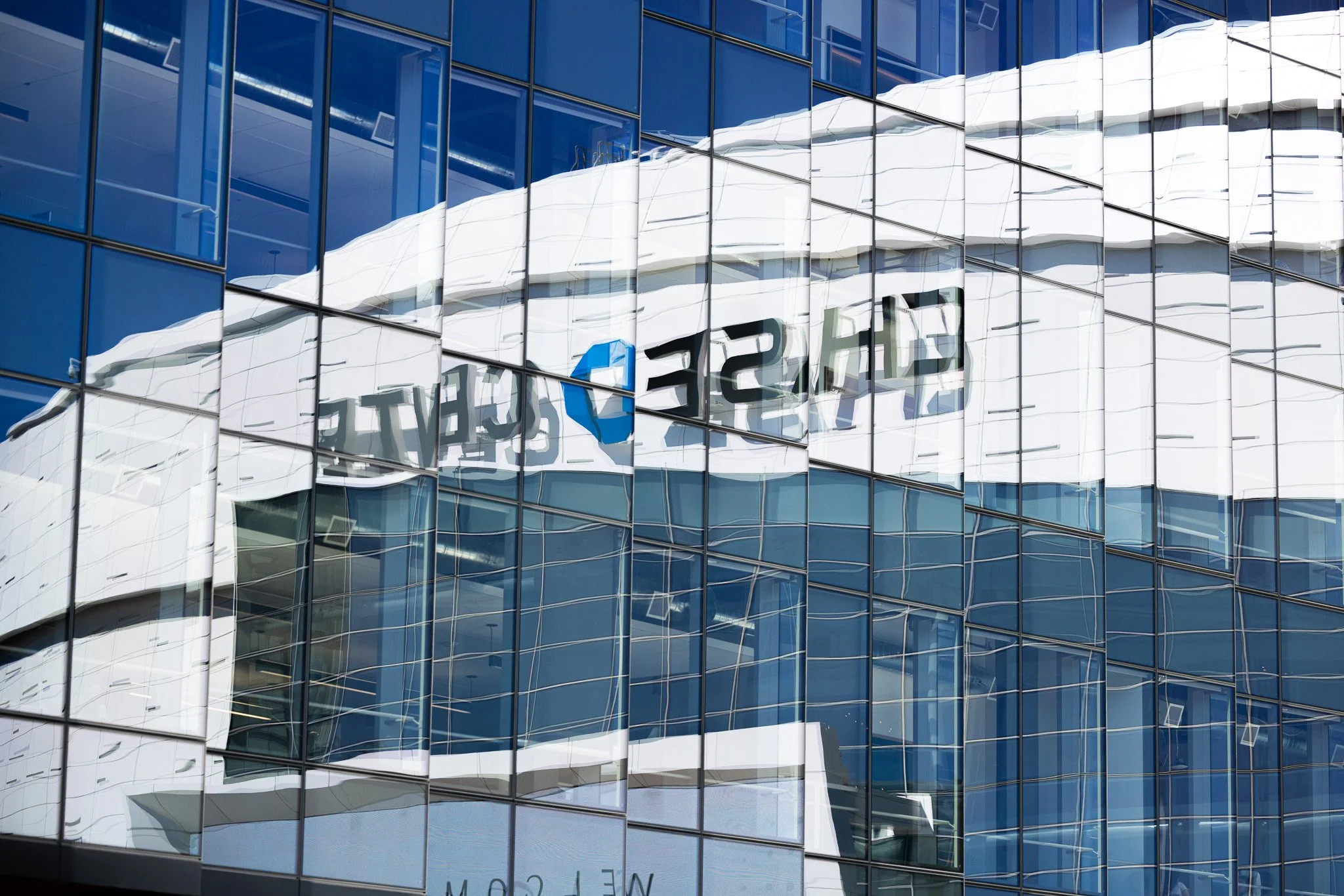 Reflection of a building with large glass windows and a sign that reads 'Sears World'.