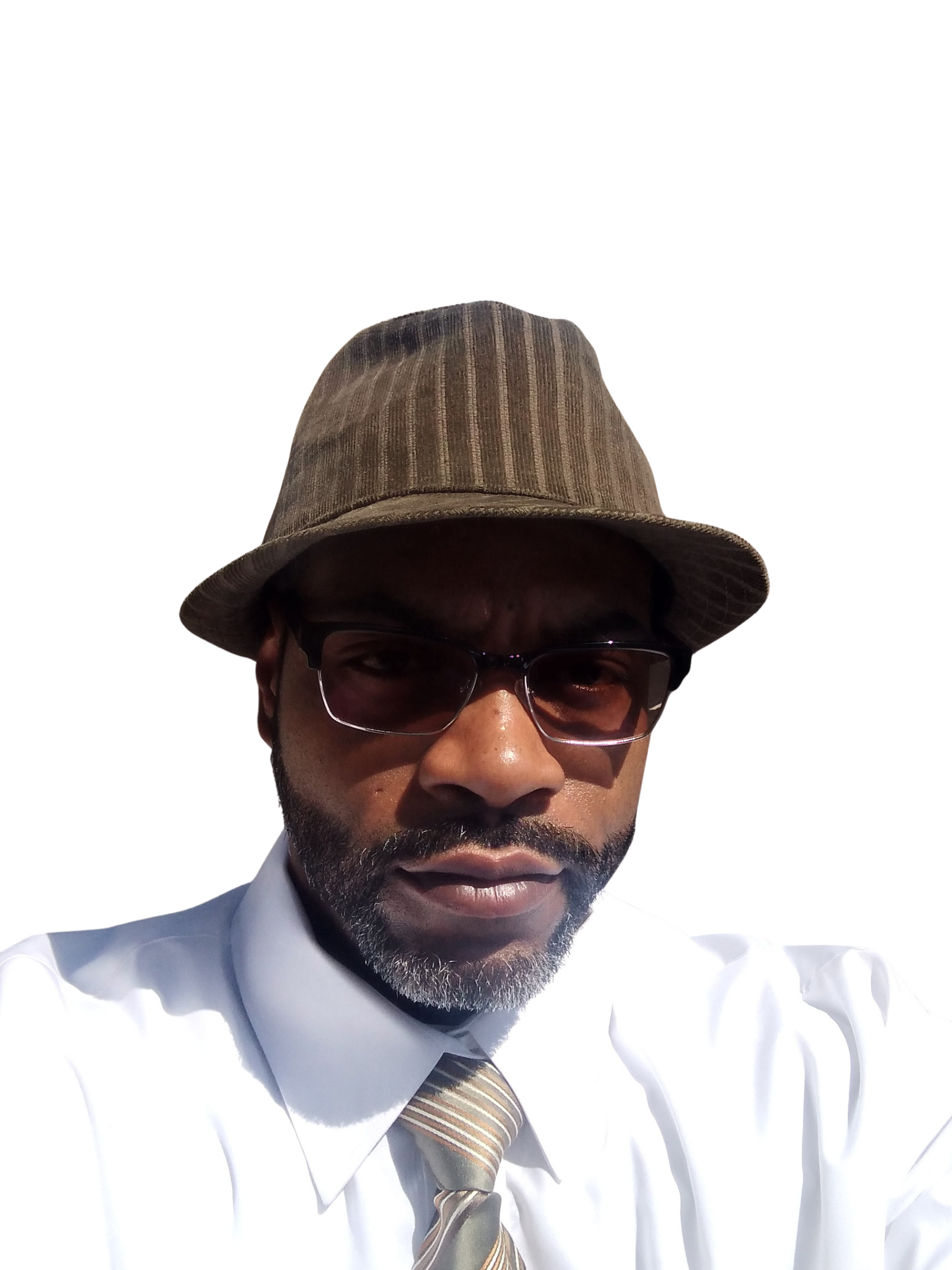 A man with dark skin, wearing glasses, a brown fedora hat, a white dress shirt, and a striped tie, is looking directly at the camera.
