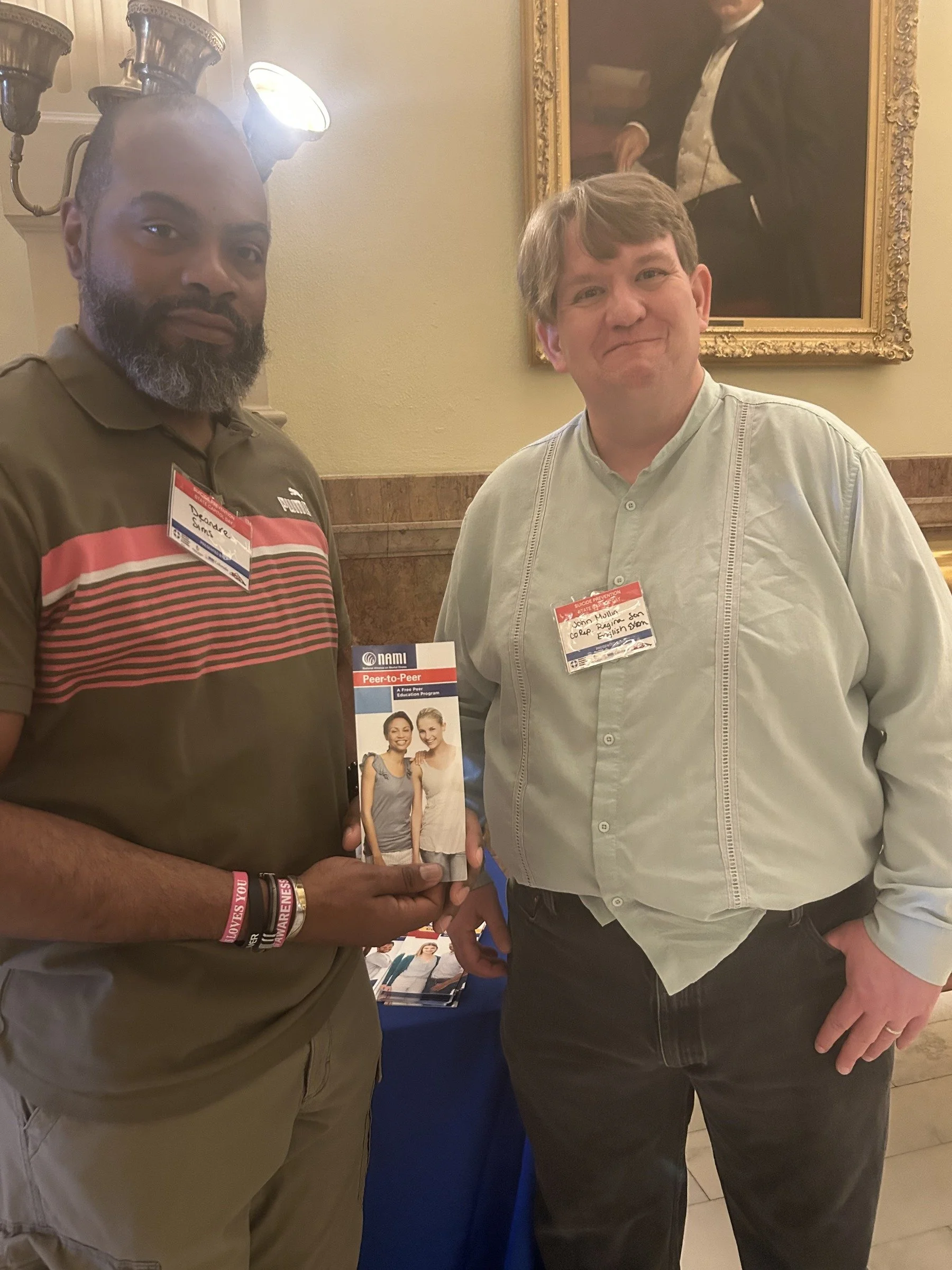 Two community advocates holding a NAMI Peer-to-Peer resource brochure.