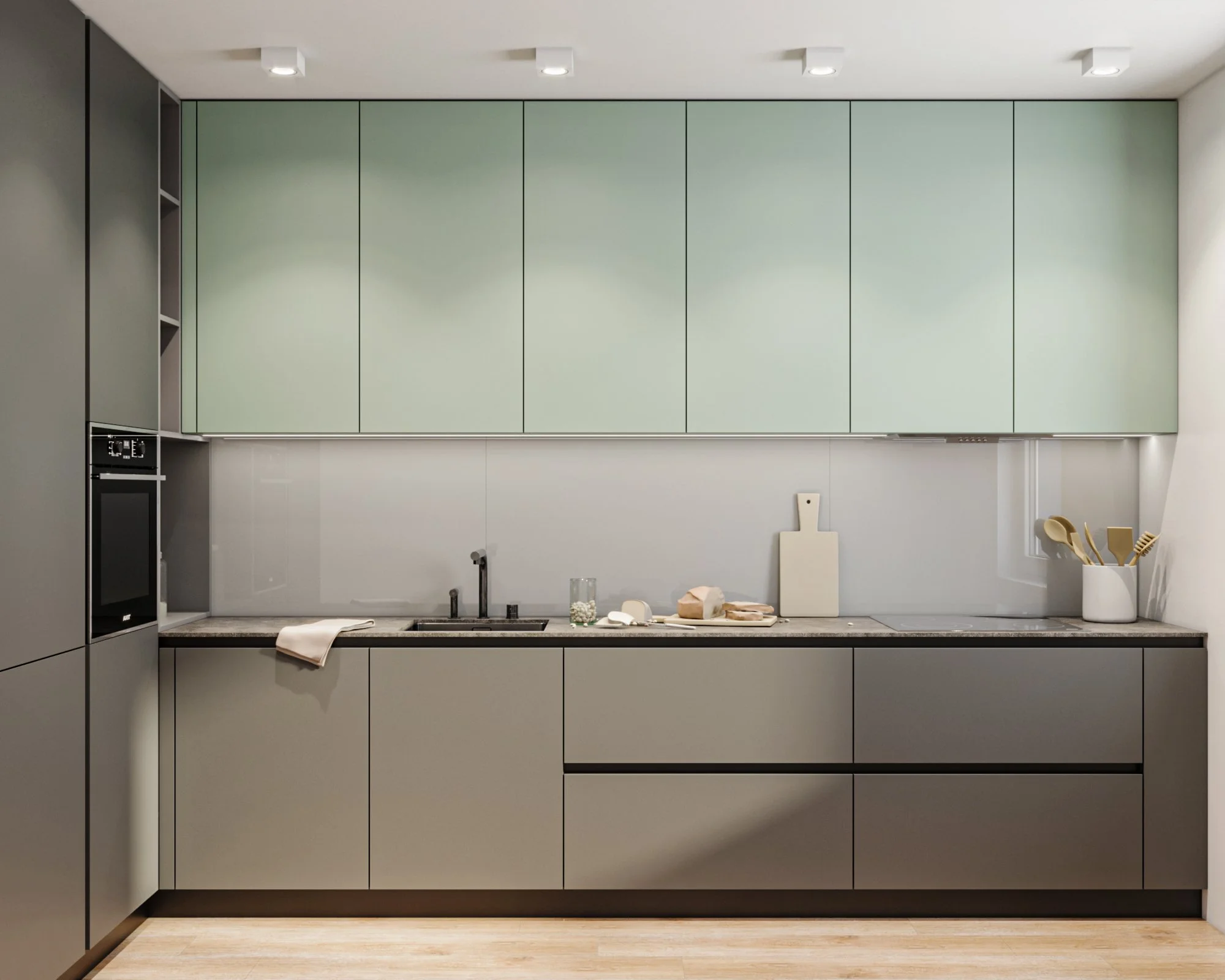 Modern kitchen with green cabinets, built-in oven, and gray countertop, with utensils in a white container on the right.