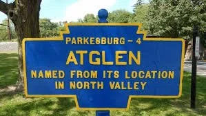 Blue historical marker sign with yellow lettering about Atglen, Pennsylvania, noting it is named for its location in North Valley, near Parkesburg.