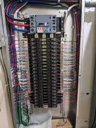 Electrical breaker panel with multiple circuit breakers and colorful wiring.