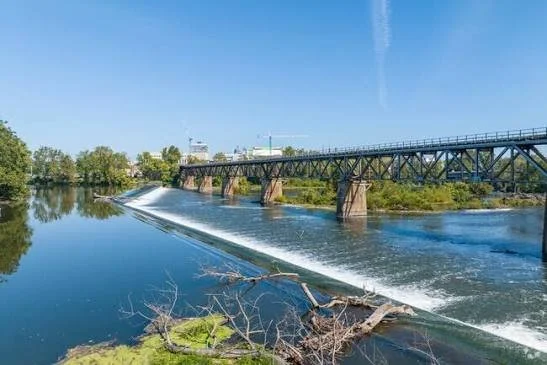 River with dam and bridge under a clear blue sky.