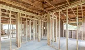 Interior of a house under construction with exposed wooden framing and ceiling joists.