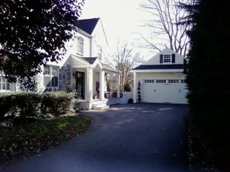 Front view of a house with a two-car garage in a suburban neighborhood during winter with bare trees.