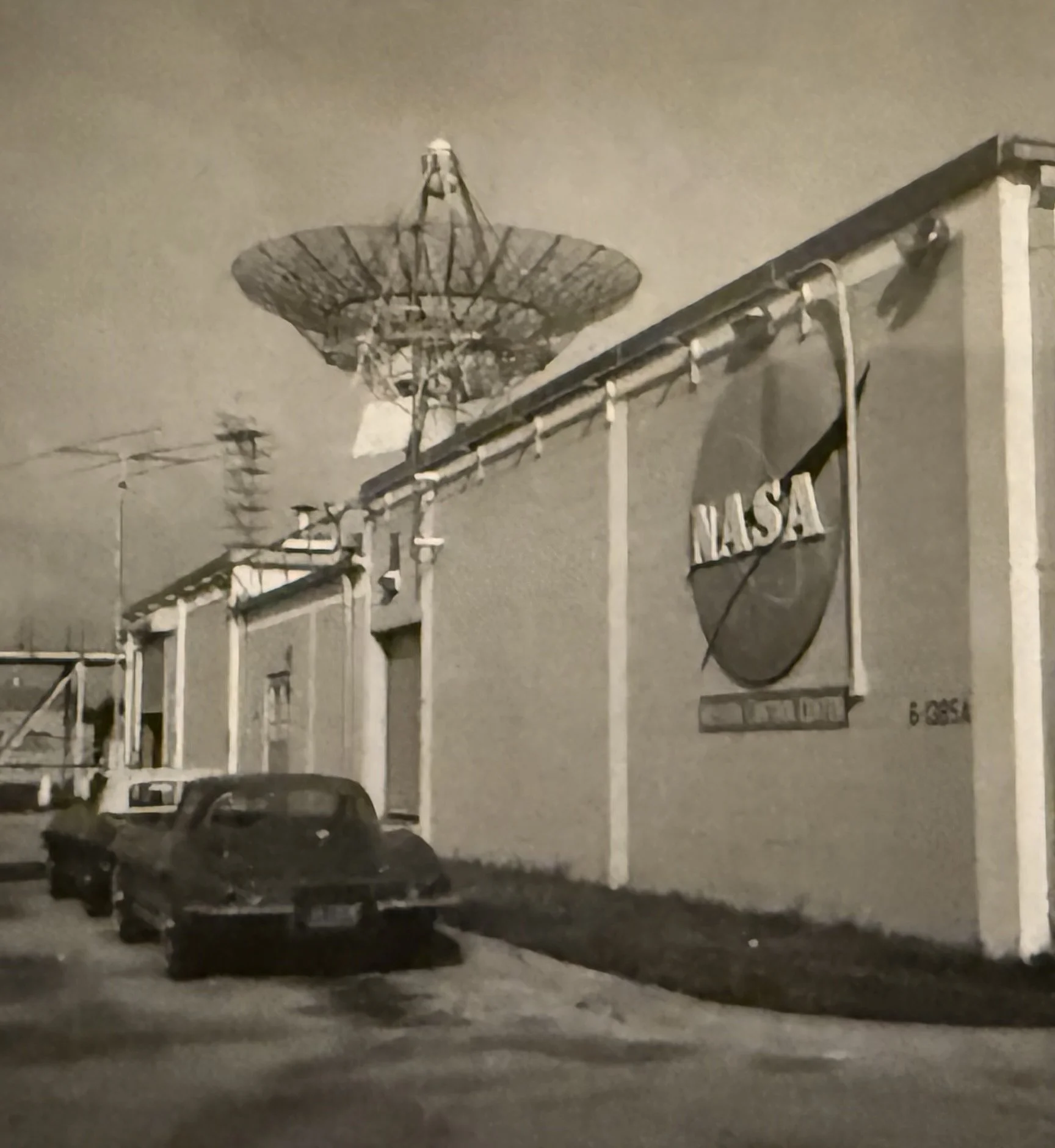Black SUV parked near a building with a signage that reads 'MARTA', with a large satellite dish on the roof. The image appears to be taken at night or during low light conditions.