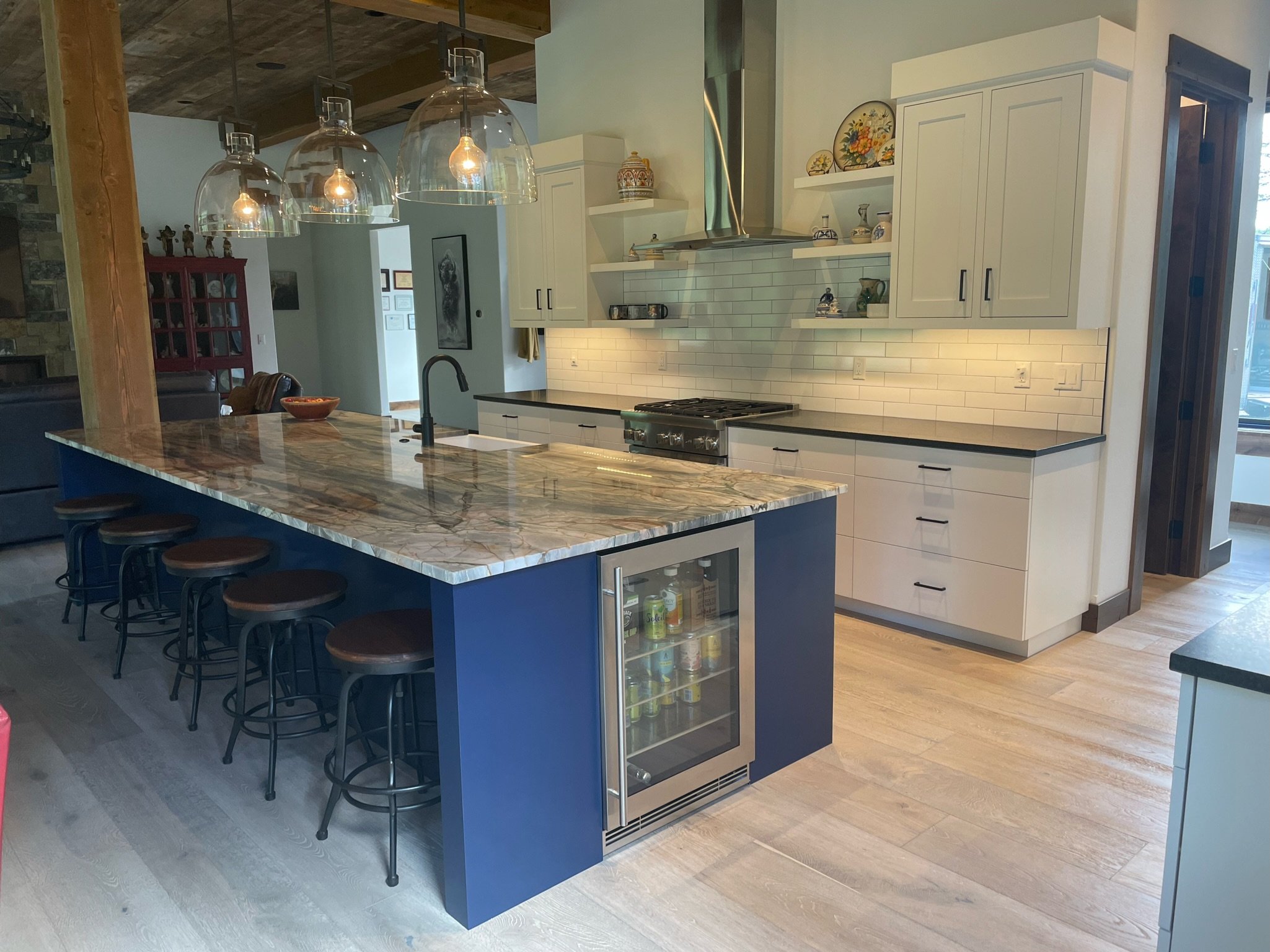 Modern kitchen with a large marble island, white cabinets, a stainless steel stove, and pendant lighting.