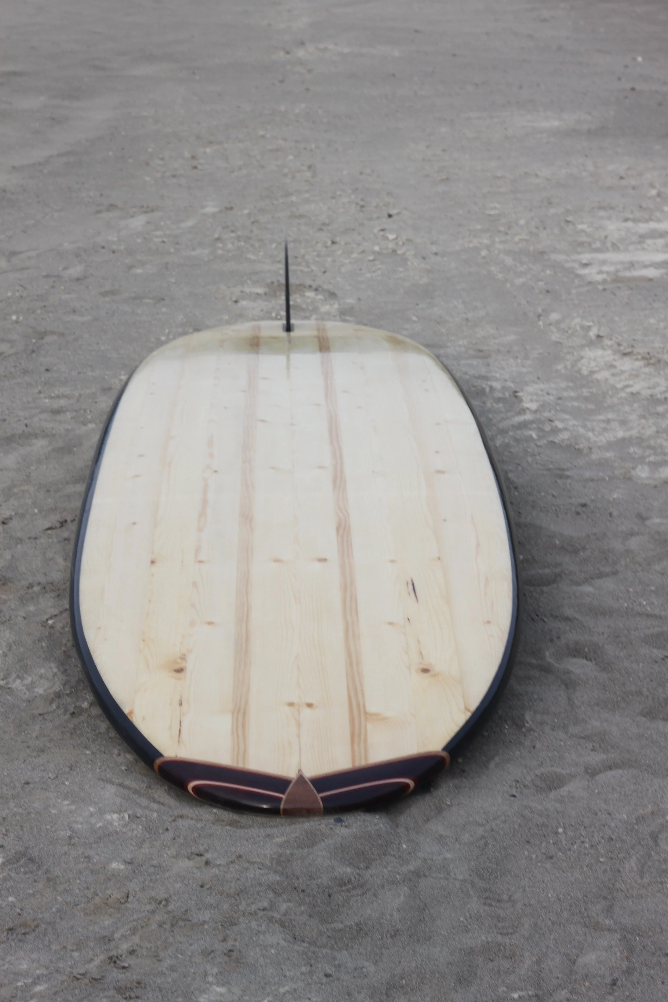Snowboard with a wooden surface lying on a sandy ground