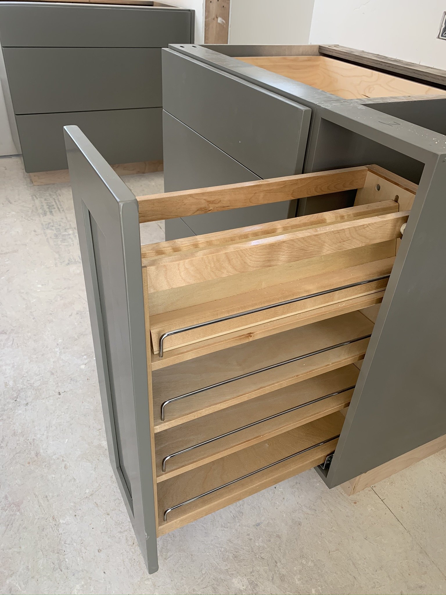 Partially assembled kitchen cabinet with gray and wooden finishes in a construction area.