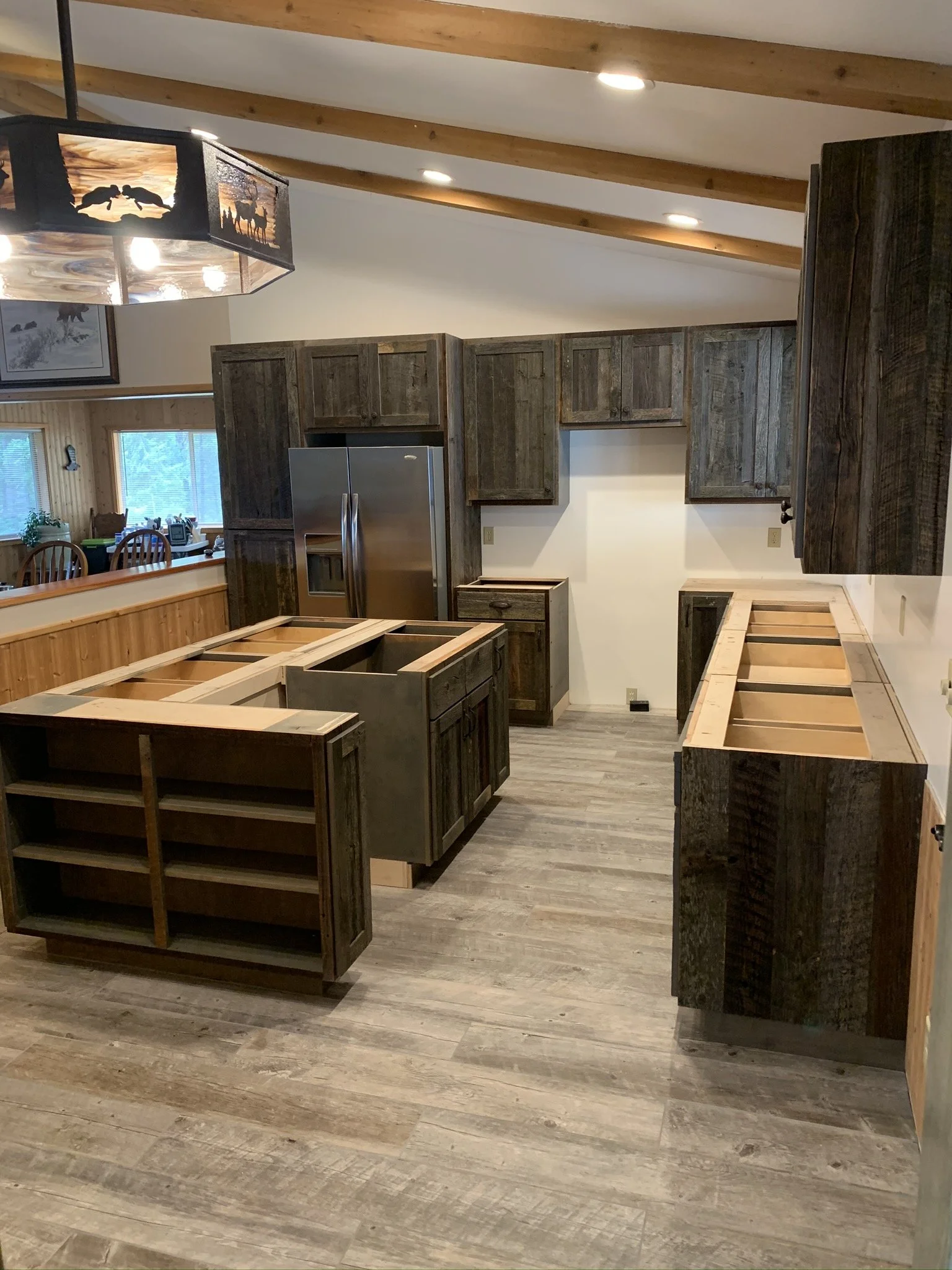 Interior of a kitchen under renovation with unfinished cabinets, new appliances, and wood flooring.