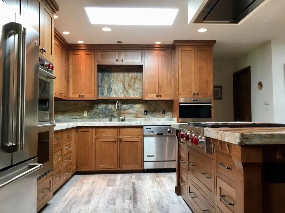 Kitchen with wooden cabinets, stainless steel appliances, a marble countertop, and a skylight.