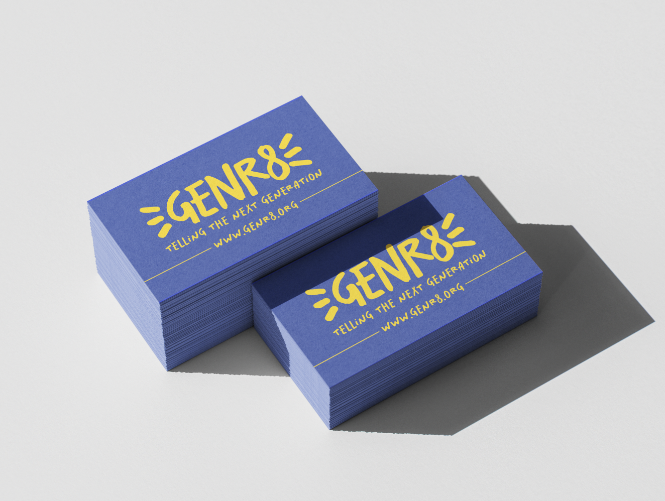 Stacks of blue business cards with yellow writing that say "GENR8" and "TELLING THE NEXT GENERATION" with a website link www.genr8.org, on a white surface.