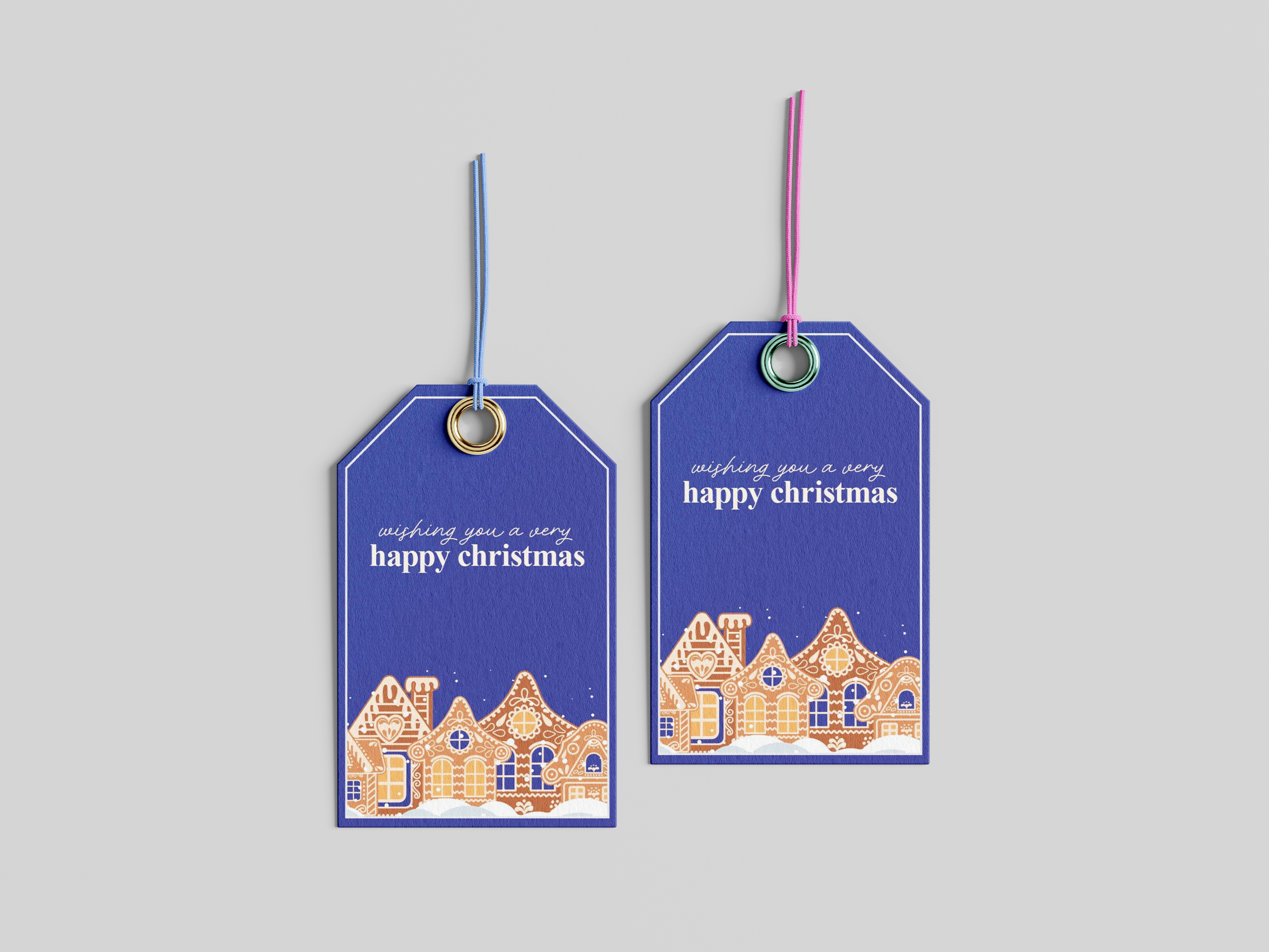 Two blue Christmas gift tags with gold and pink loops, featuring winter village scenes and the message 'wishing you a very happy Christmas' on each.