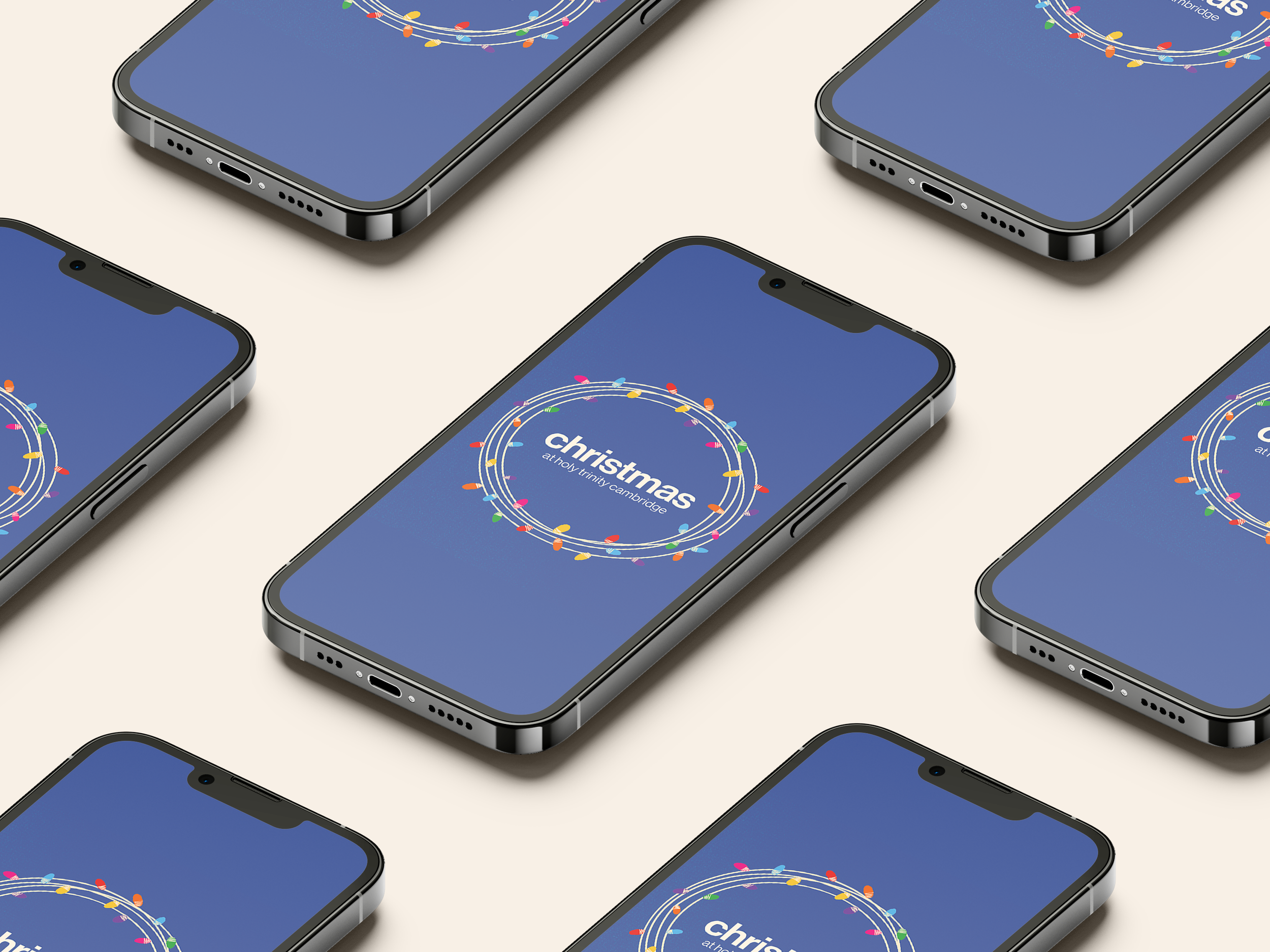 Multiple smartphones lying on a flat surface, displaying a Christmas-themed message with colorful holiday lights around the text that says "Christmas at Holy Trinity Cambridge."