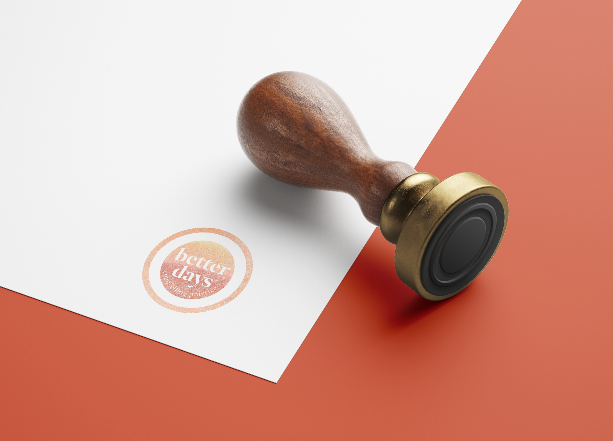 A rubber stamp with a wooden handle and a brass collar, resting on a white paper with an orange circular logo that says "better days" and the words "coaching & practice" beneath, on an orange surface.