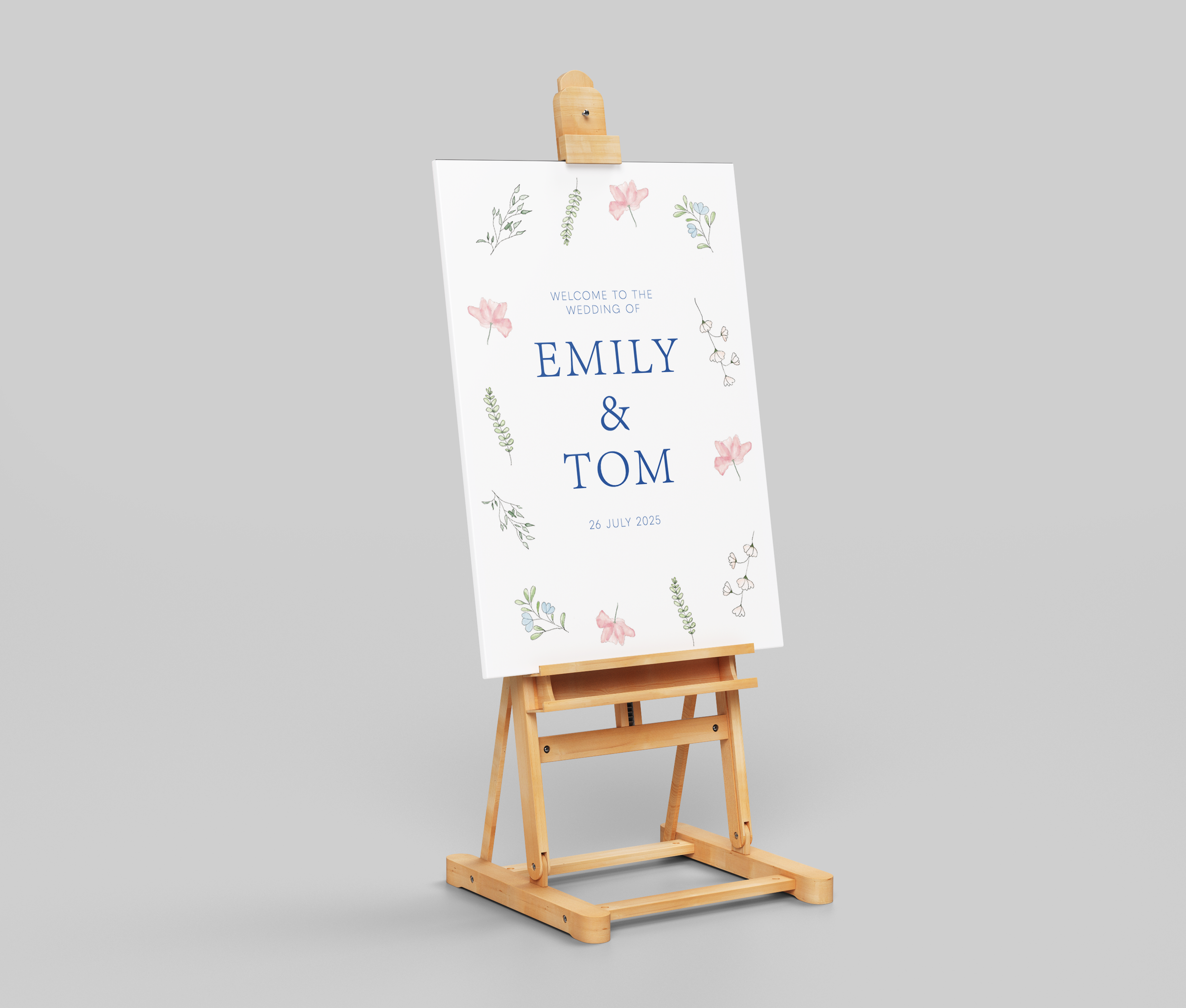A wedding sign on a wooden easel with floral illustrations and blue text that reads "Welcome to the wedding of Emily & Tom, 26 July 2025."